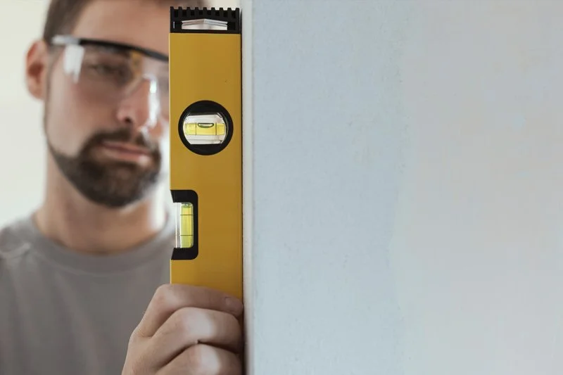 Allure Glass installer measuring a wall prior to glass shower installation
