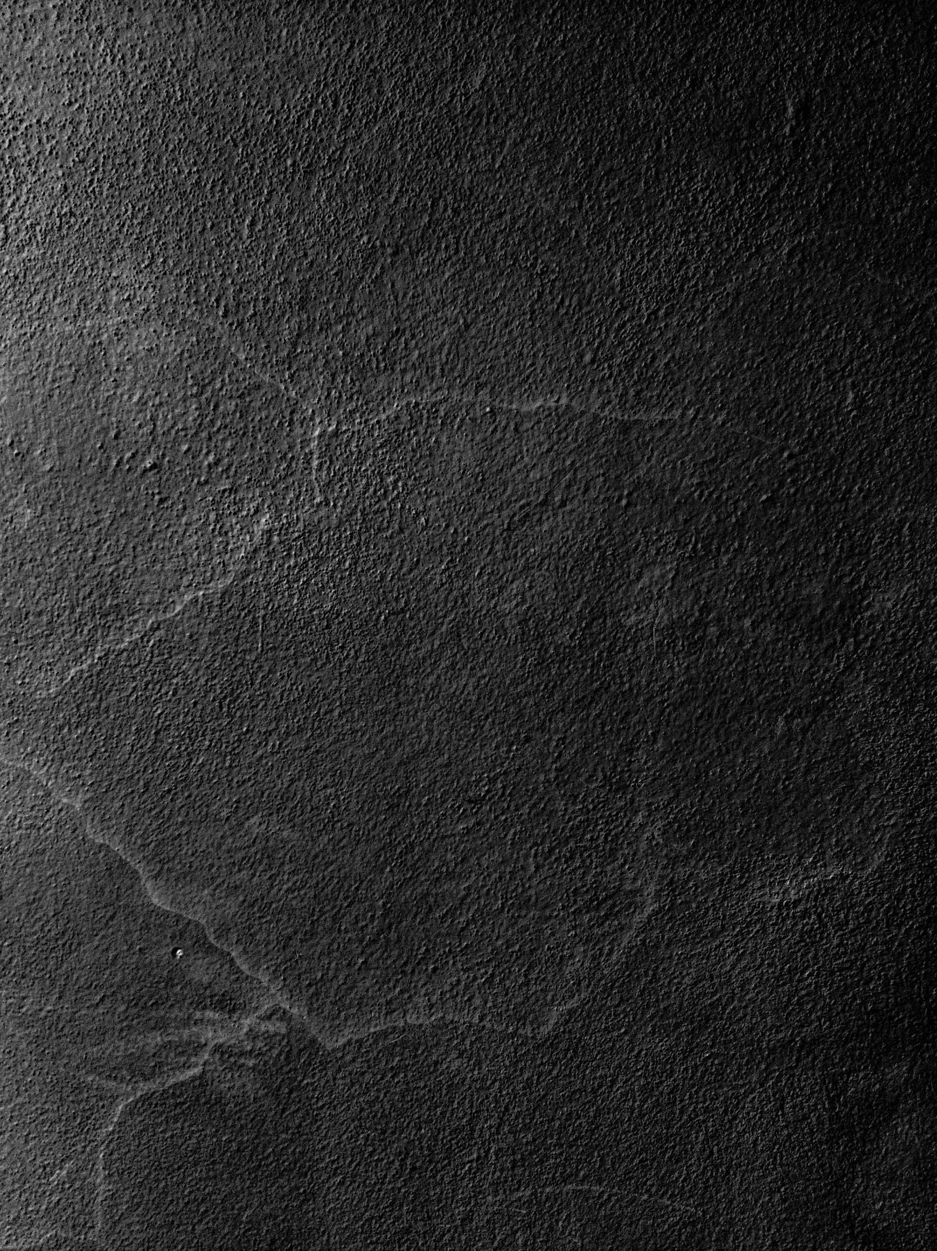 Close-up of a dark, textured surface with faint scratches and cracks.