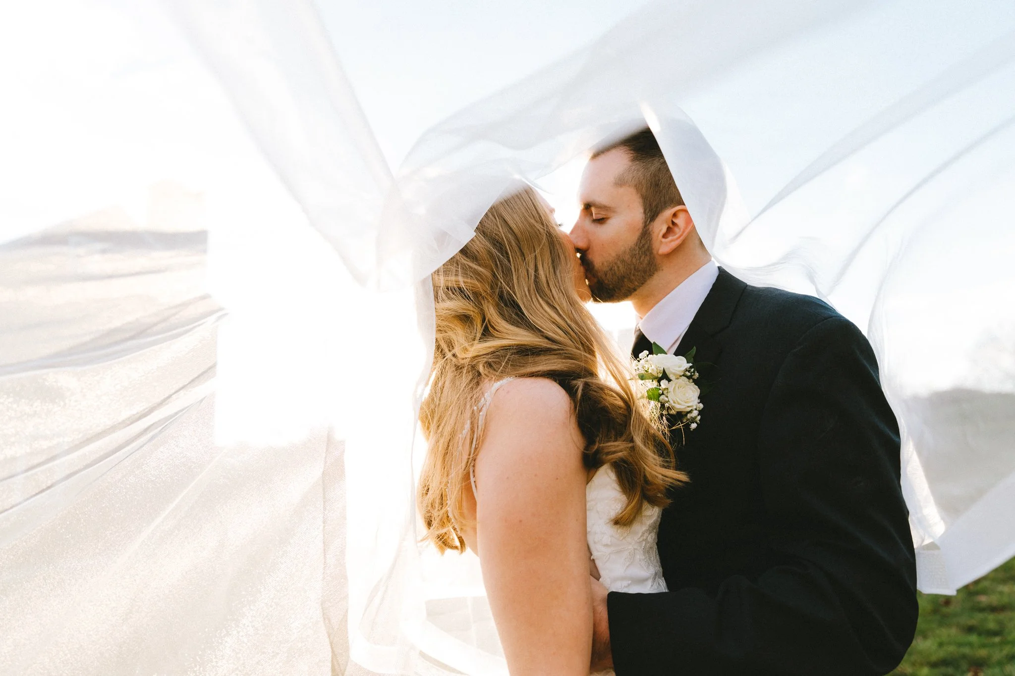 ride and groom sharing a first kiss under a flowing veil, romantic Maryland wedding photography by Love Story By Aira