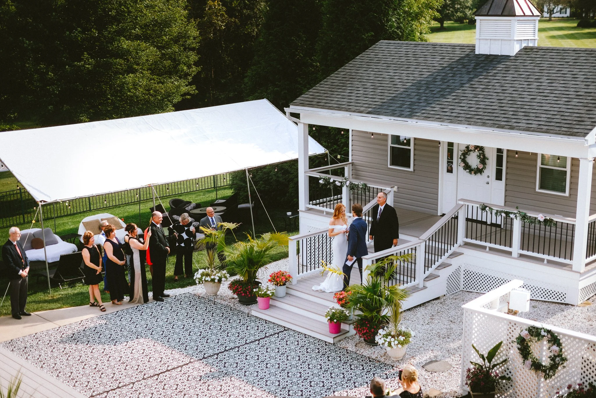 Aerial view of intimate backyard wedding ceremony with bride groom and officiant on the porch steps, documentary photography
