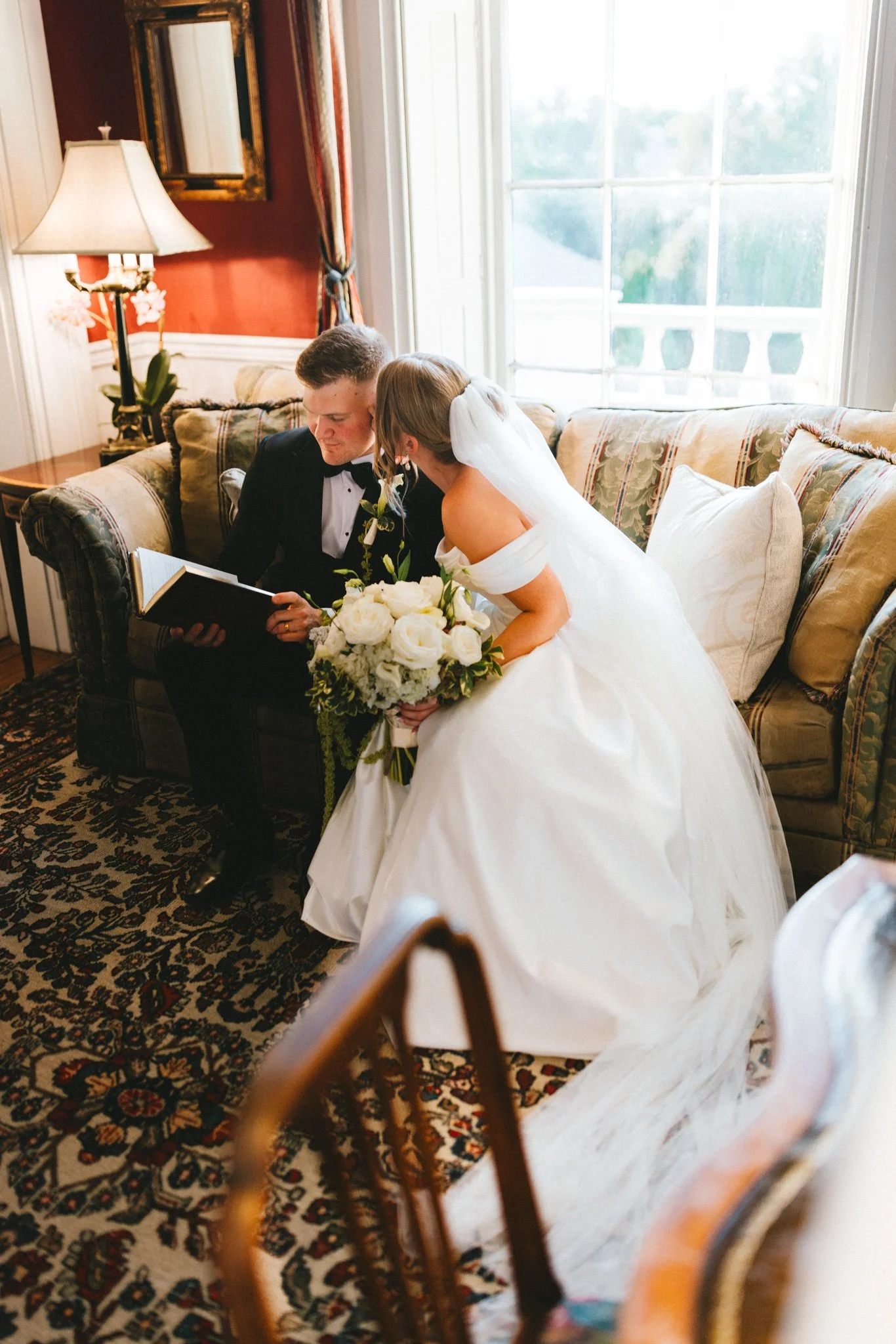 Bride and groom sharing an intimate moment reading vows together on a vintage sofa, documentary wedding photography by Love Story By Aira Maryland. Wedding Photography packages,