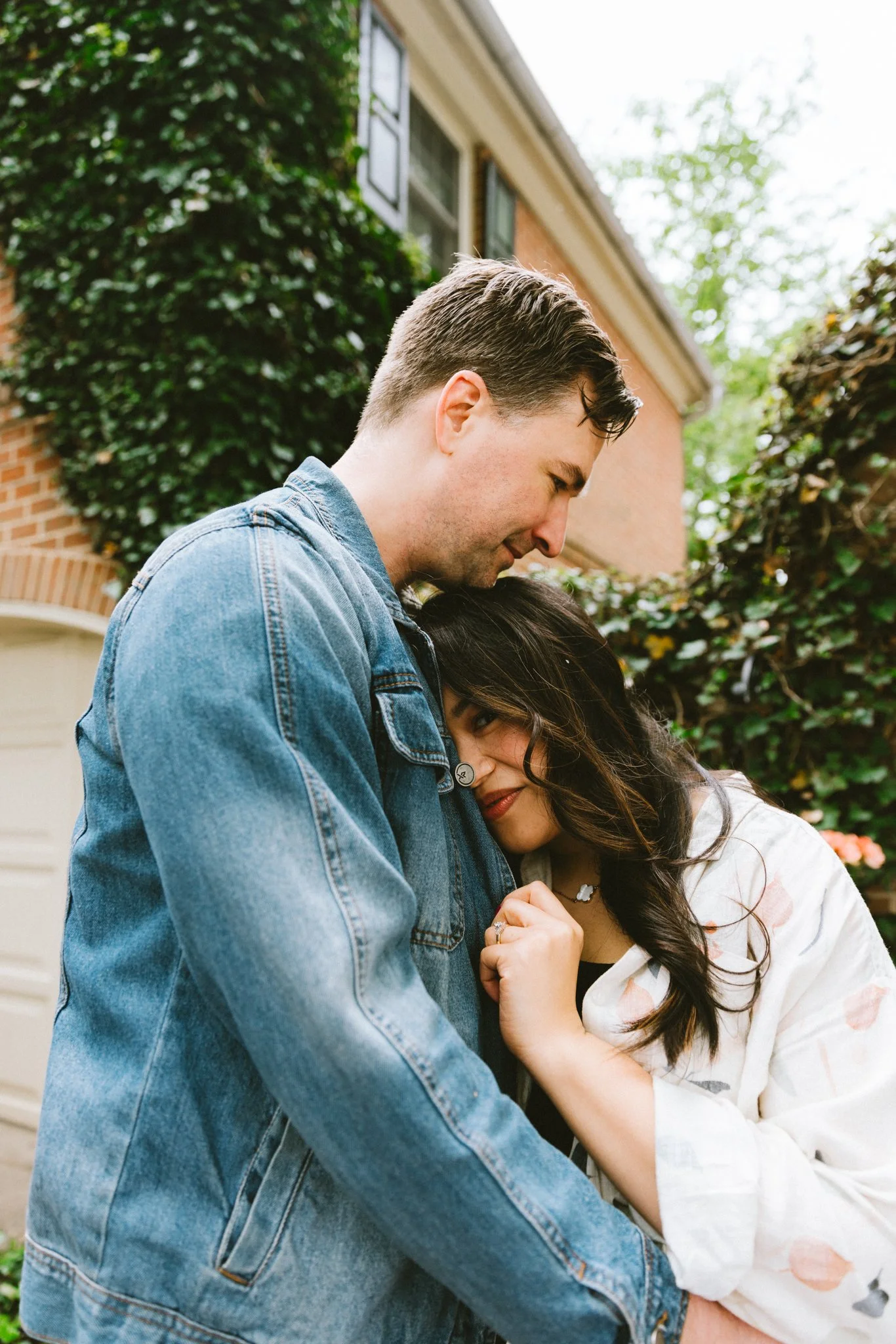  She leaning her head against his chest, both quiet and close, ivy-covered brick wall behind them 
