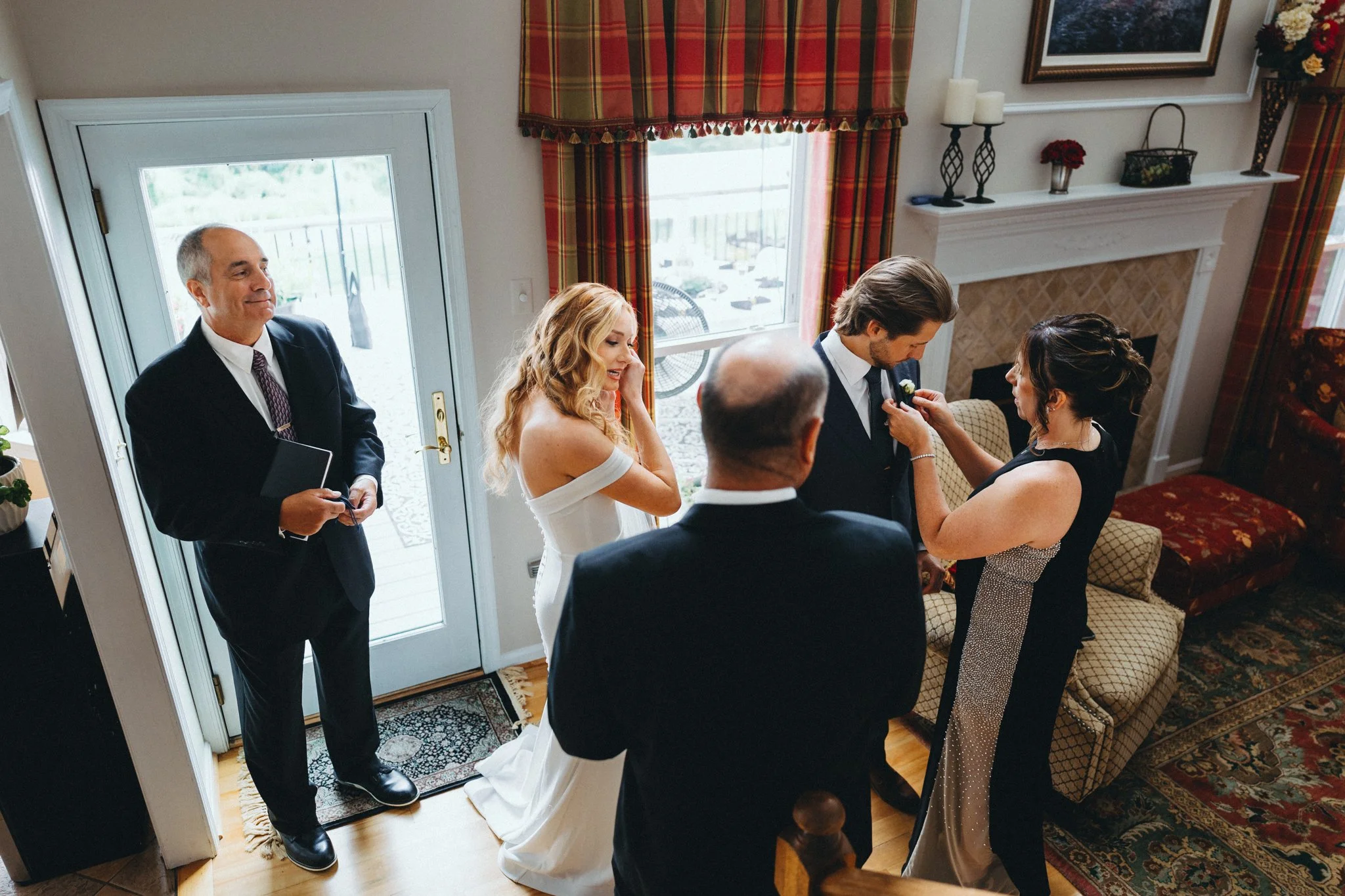 Family helping groom pin boutonniere during getting ready, warm candid moment at their Maryland home.