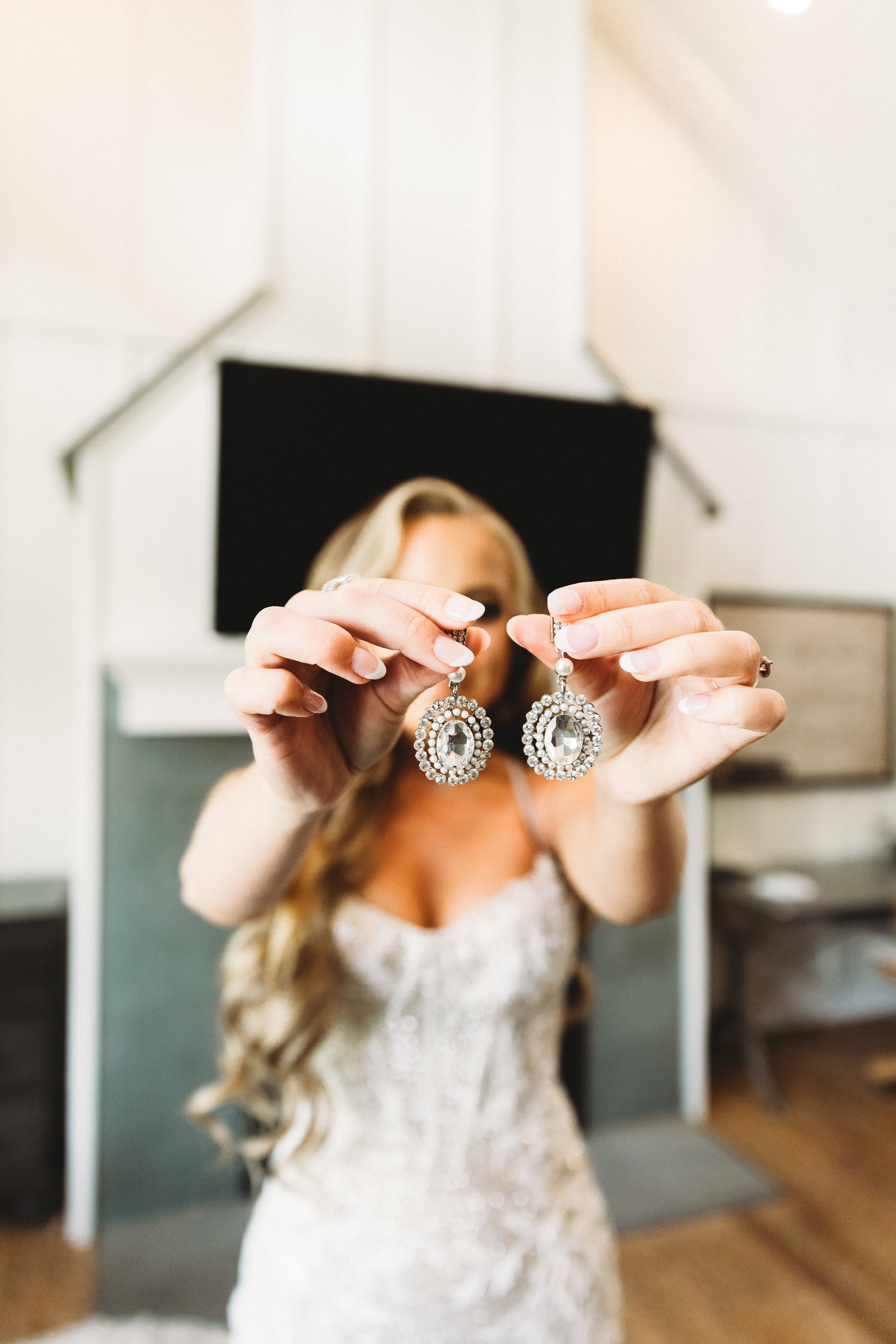 bride holds diamond earrings