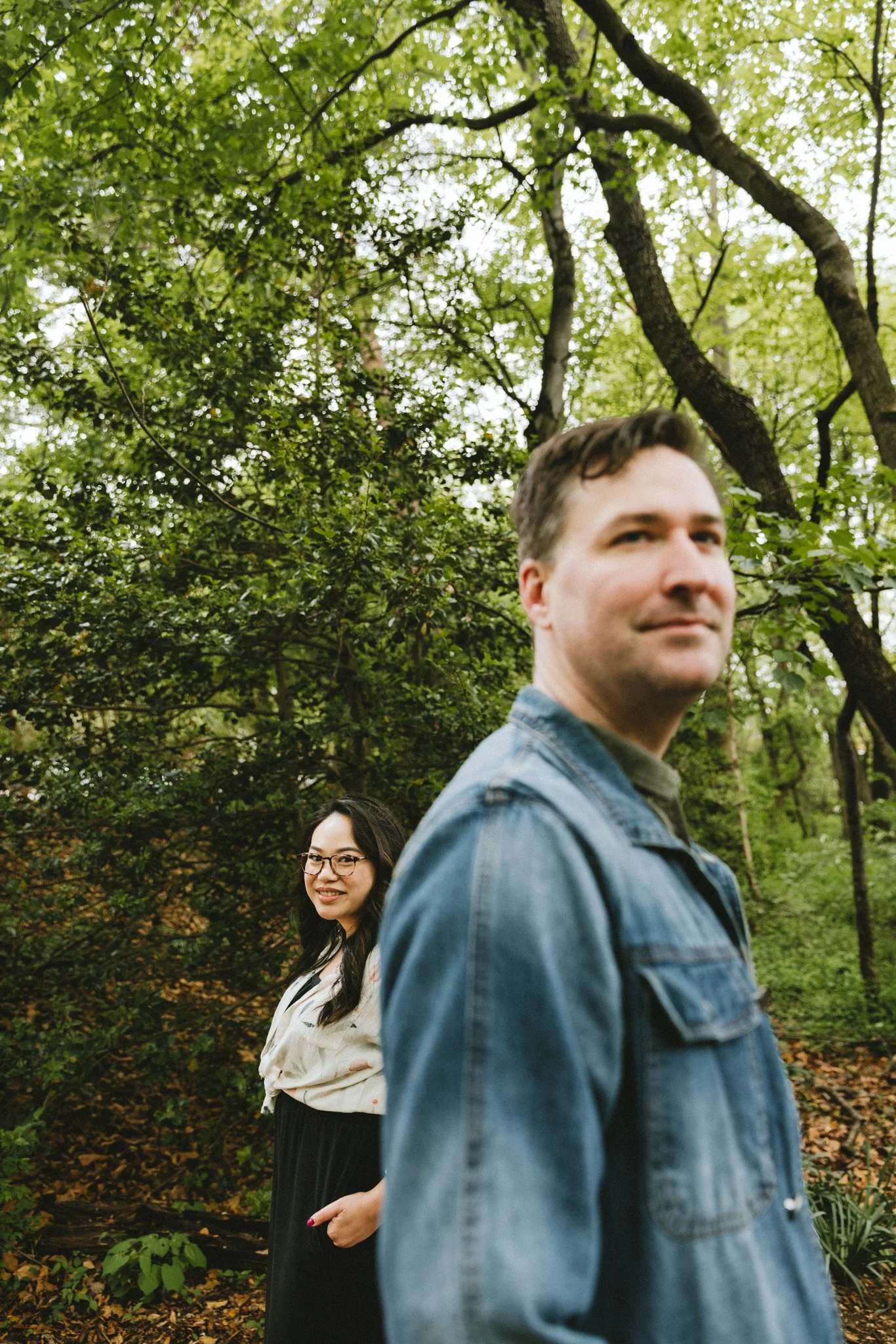  Ryan in soft focus in the foreground, Mariel smiling at him from behind among the spring trees at Gaithersburg, Maryland 