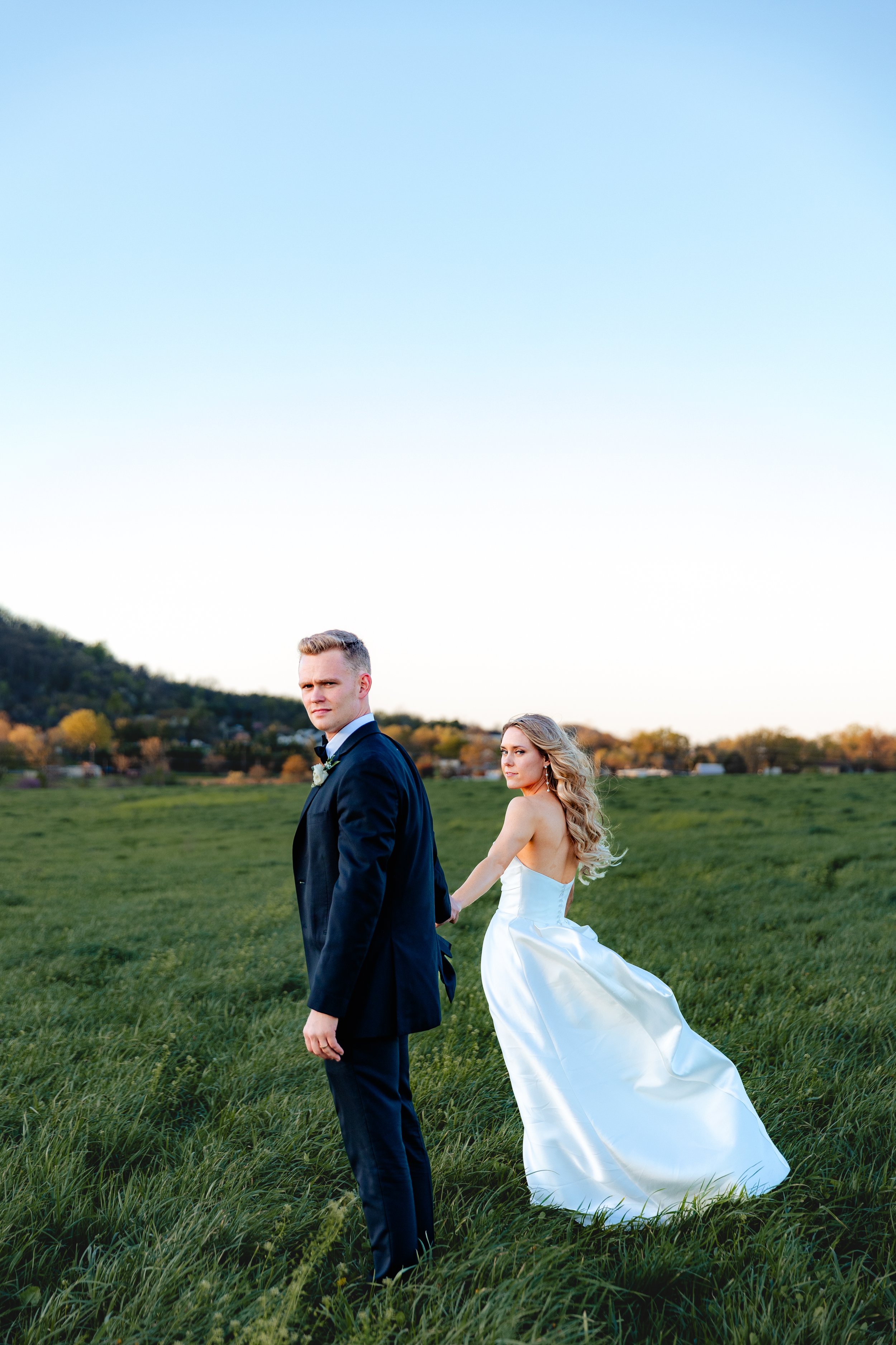 groom leads bride walking on the grass