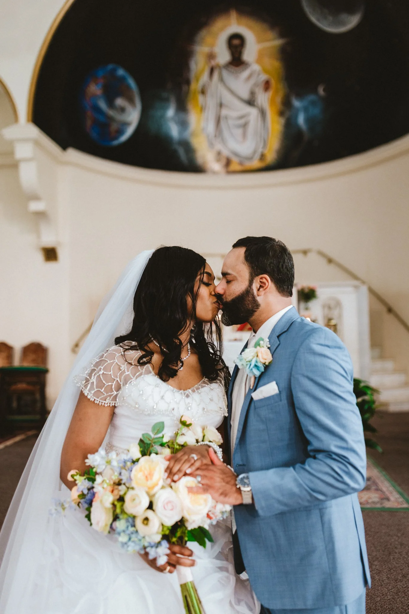 Bride and groom sharing first kiss during church wedding ceremony