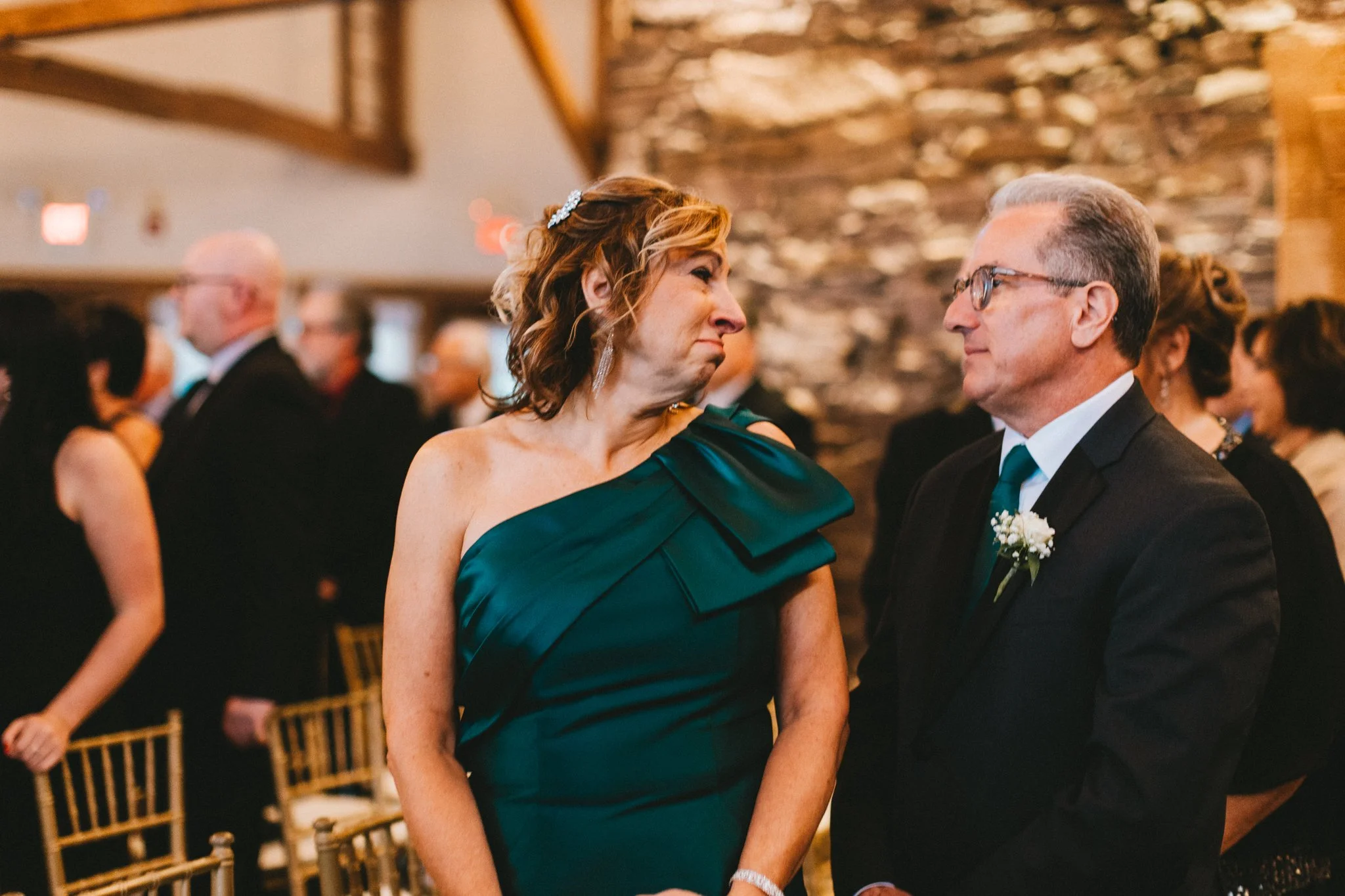 Mother of the bride in a green gown, tearful glance with the father of the bride — documented by Love Story By Aira
