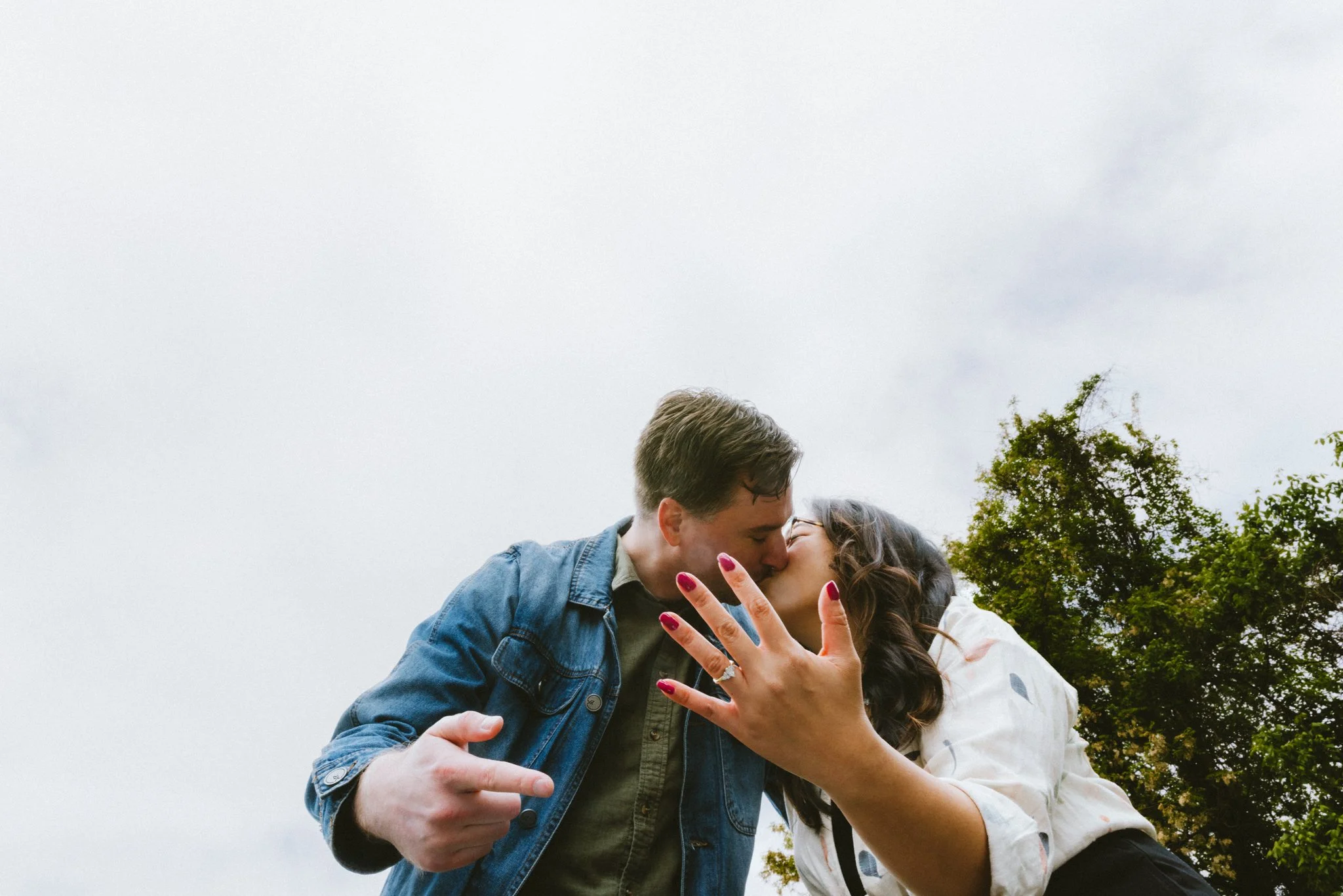  Mariel and Ryan kissing while she holds up her engagement ring toward the camera, laughing — Love Story By Aira Photography 