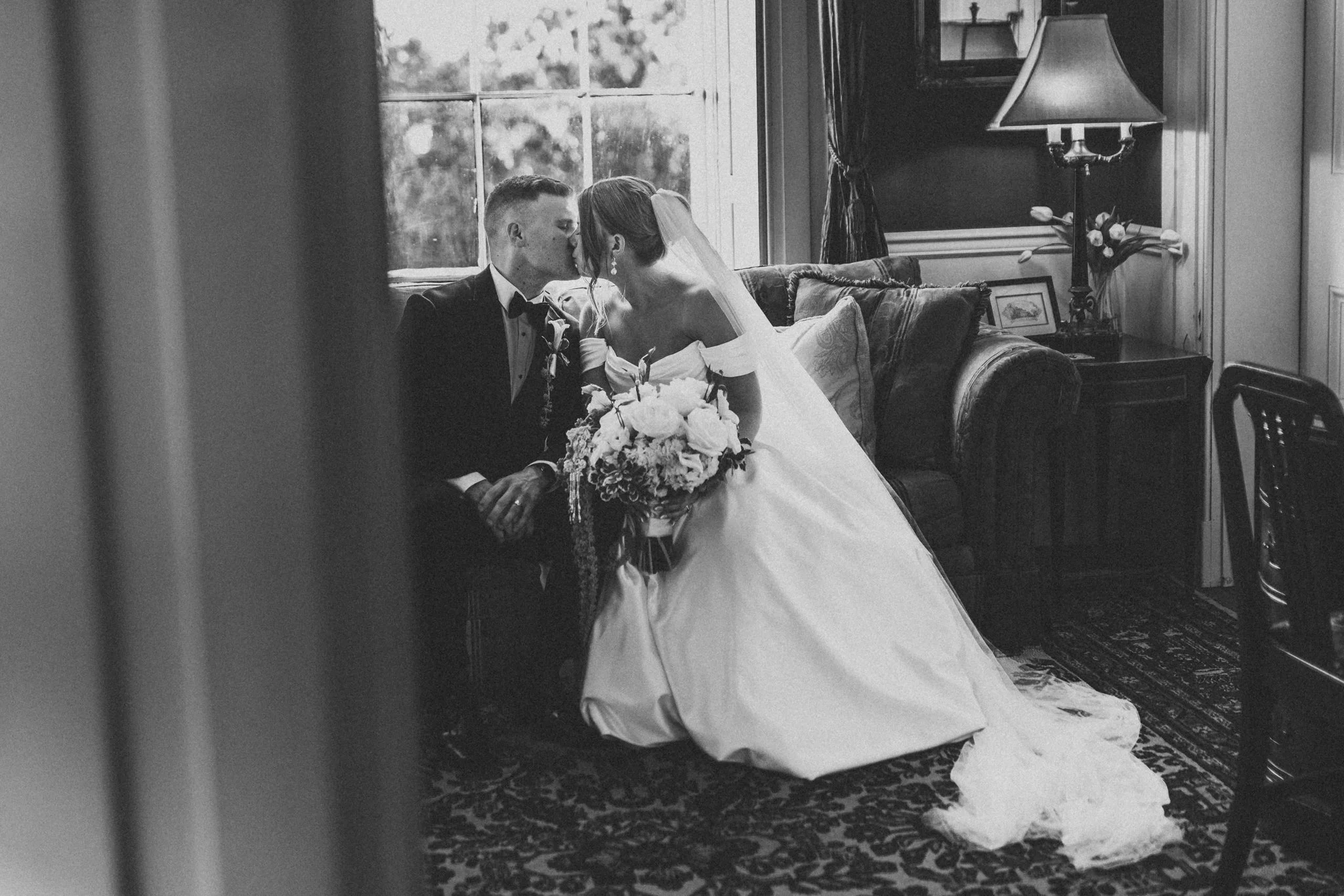 Bride and groom sharing a kiss inside Antrim 1844 historic manor sitting room, intimate indoor wedding portrait