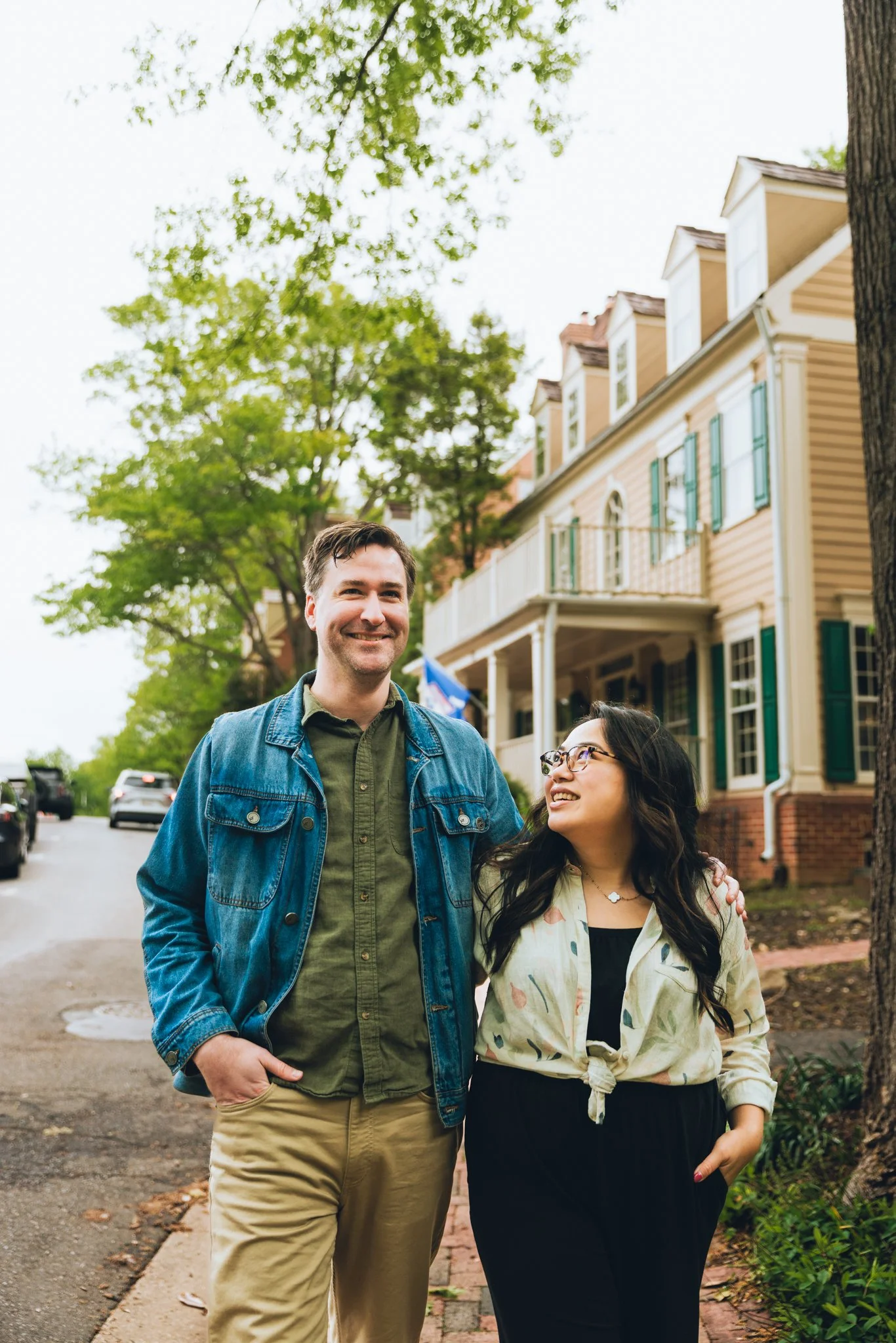  The engaged couple walking hand in hand along a brick path, both smiling 