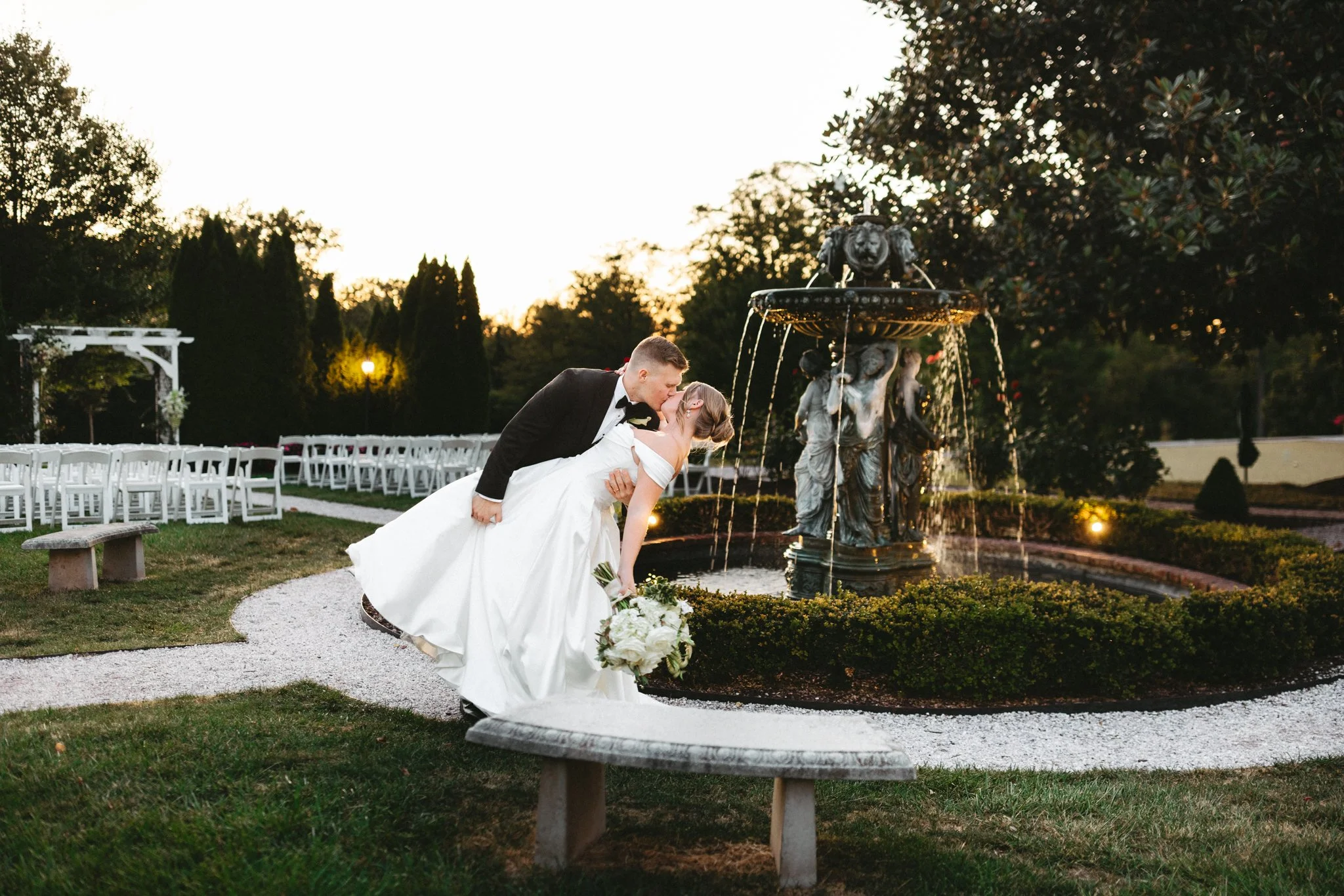 Bride and groom sharing a dip kiss in front of the fountain at Antrim 1844 at sunset, romantic Maryland wedding photography