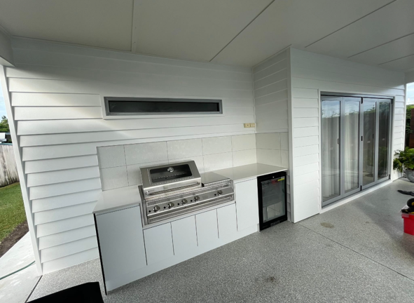 Outdoor kitchen with a built-in grill, mini fridge, countertop, and sliding glass door
