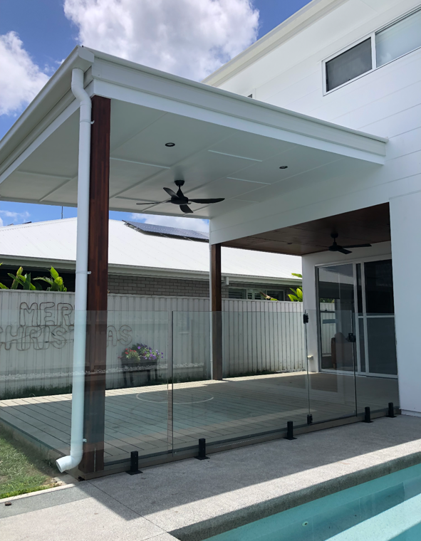 Backyard patio with glass safety fence, ceiling fans, and a covered roof, adjacent to a swimming pool.