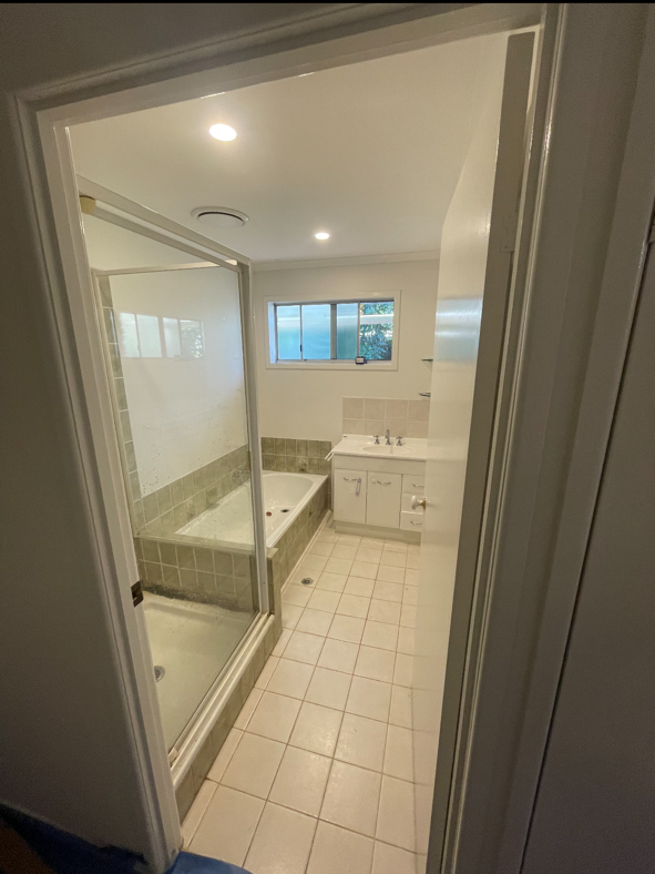 Bathroom with tiled floor, a shower stall with a glass door, a bathtub, a sink with a cabinet, and a small window above the sink.