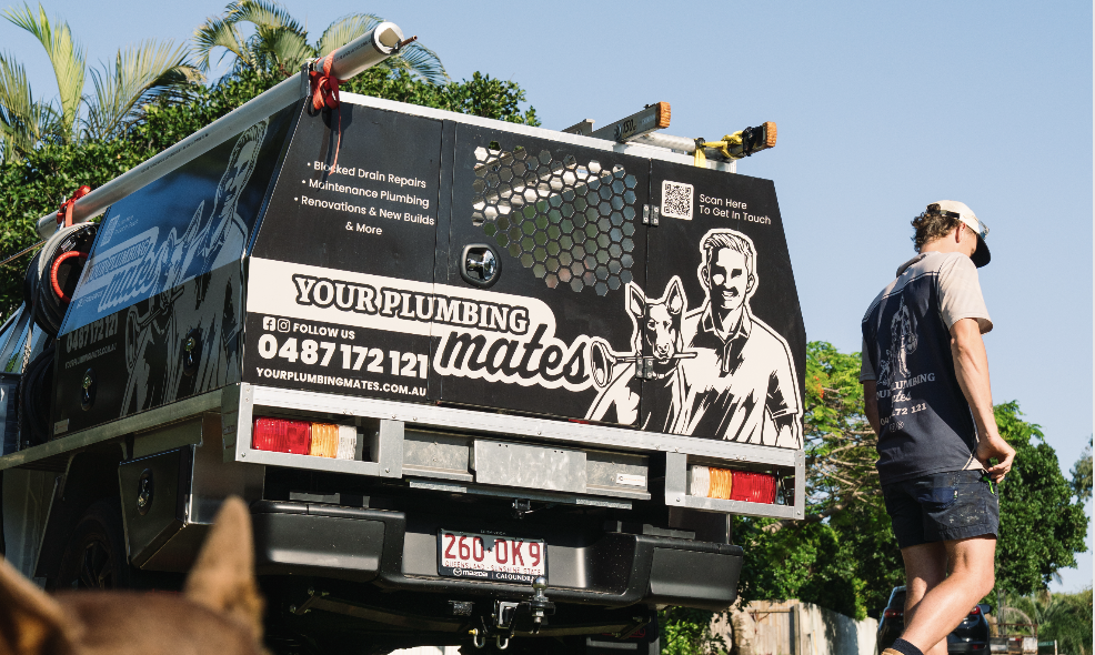Photo of one of four Your Plumbing Mates vehicles, with Riley walking and Brucey in the foreground.