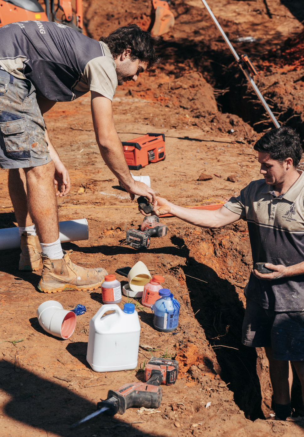 Your Plumbing Mates plumbers passing tools to each other in Woombye working on the plumbing for a residential new build project, laying pipe underground in Woombye