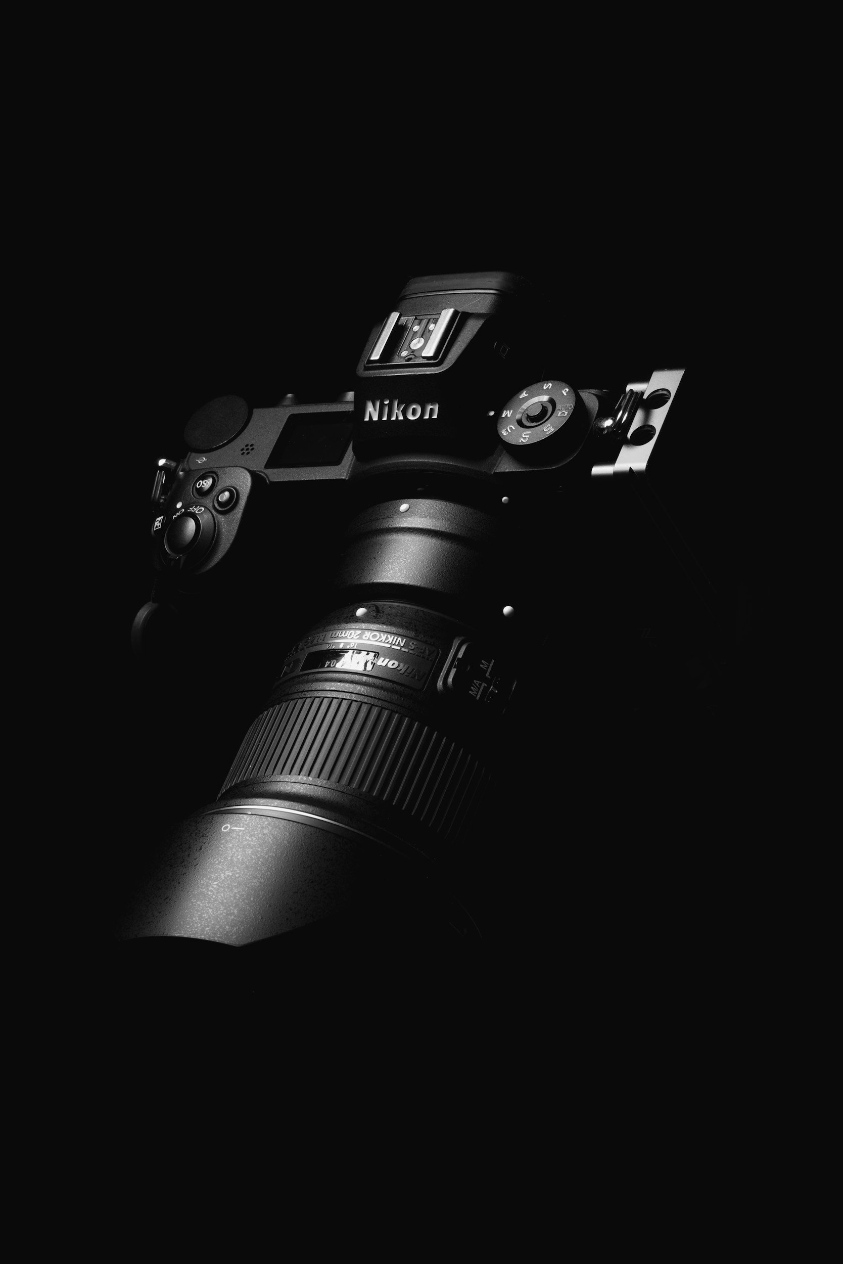 Close-up of a Nikon digital camera with a large telephoto lens, set against a black background.