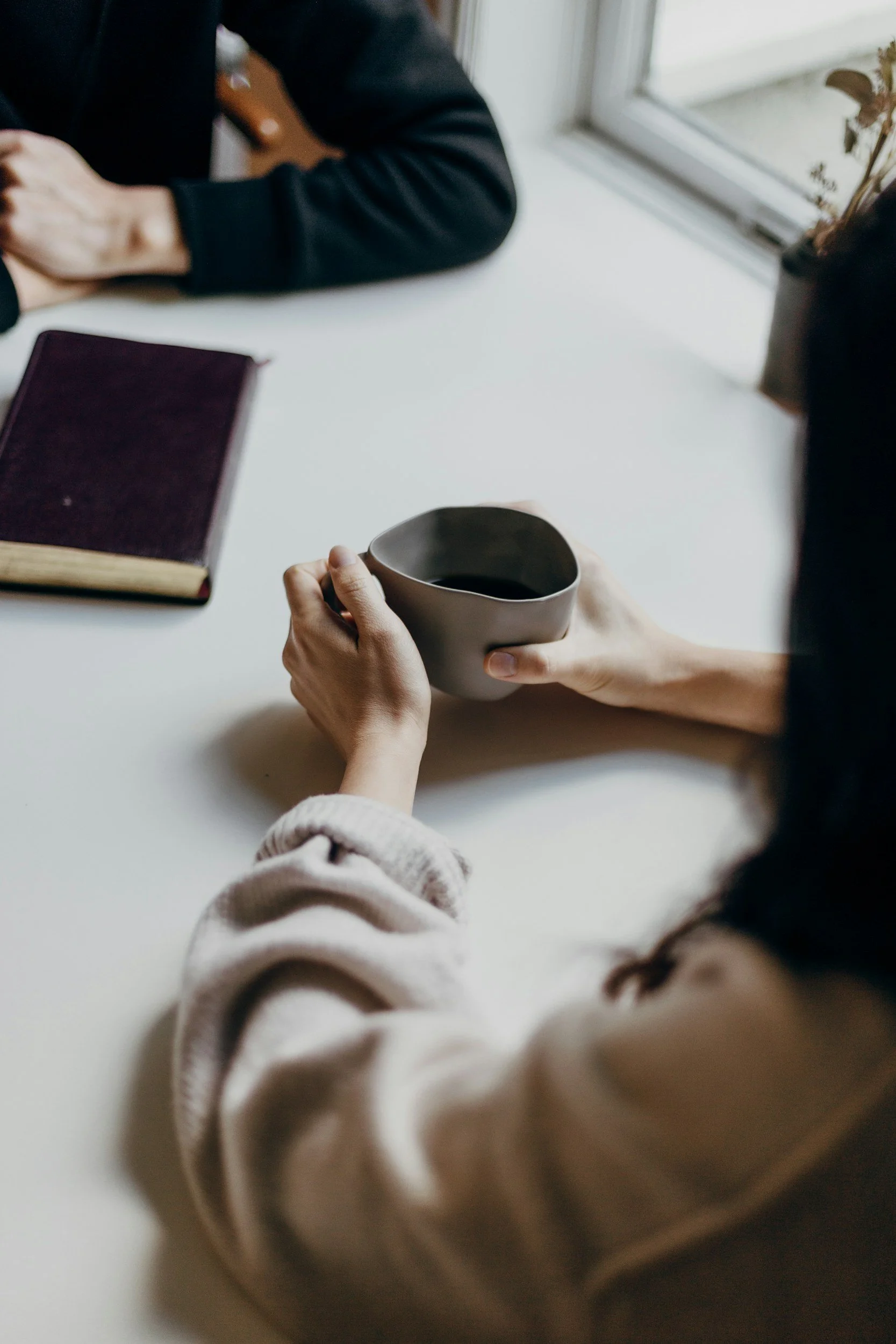 Hands holding cup of coffee while sitting at a table