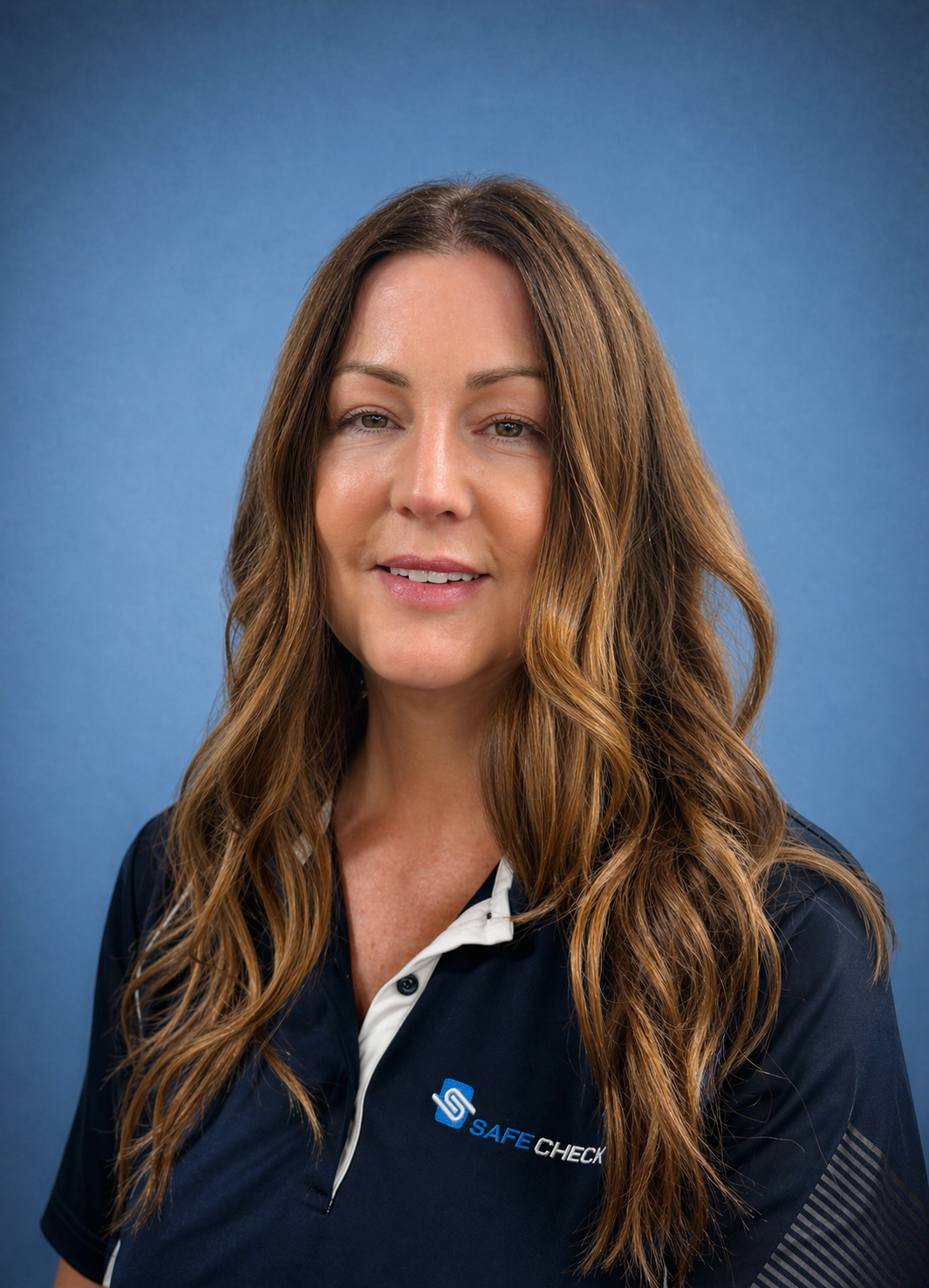 Portrait of a woman smiling, wearing a yellow and blue shirt against a blue background.