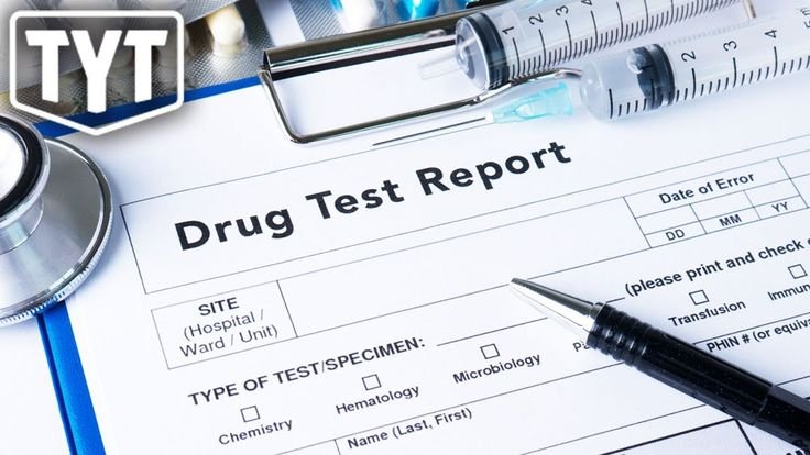 Close-up of a drug test report form with a pen, syringes, and a stethoscope on top.