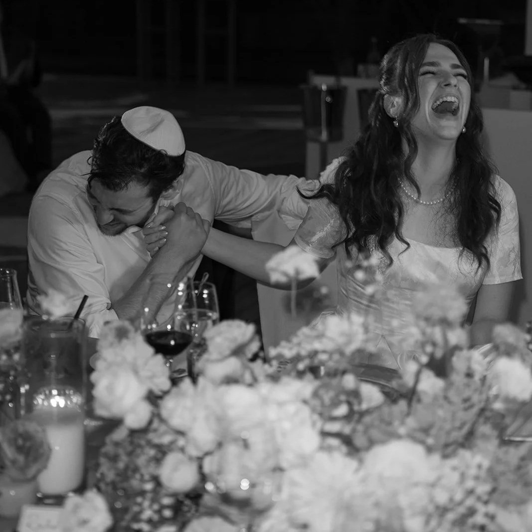 The groom and bride laughing during a speech, captured in real emotions wedding photography.