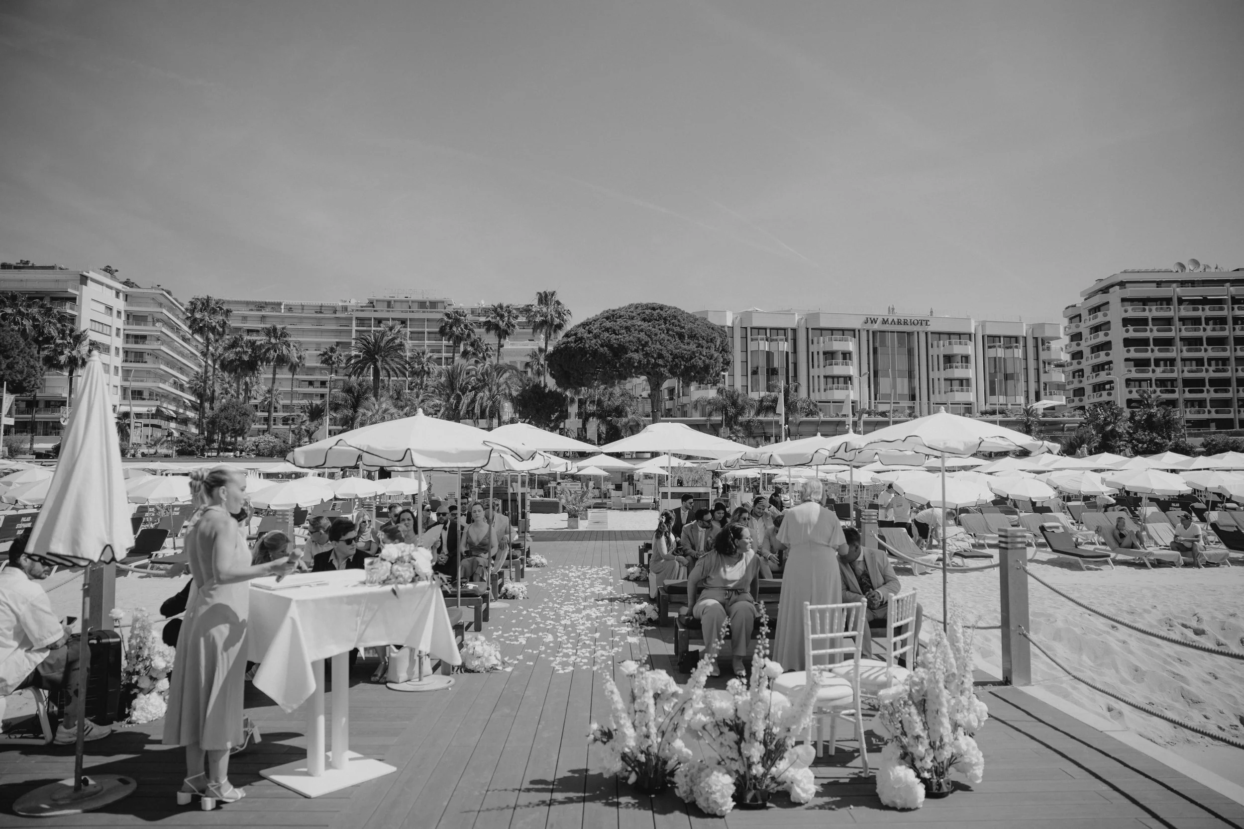 Outdoor wedding ceremony at Stephanie Beach in Cannes overlooking the Mediterranean Sea, surrounded by palm trees and the beautiful coastline of the French Riviera during an intimate luxury wedding.
