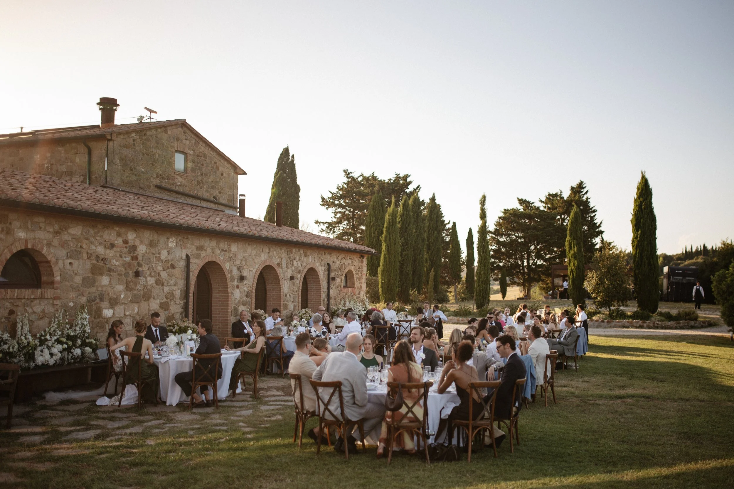 Relaxed and elegant Tuscany wedding dinner under the open sky, with natural white and green wedding styling, long summer evenings and an intimate atmosphere.
