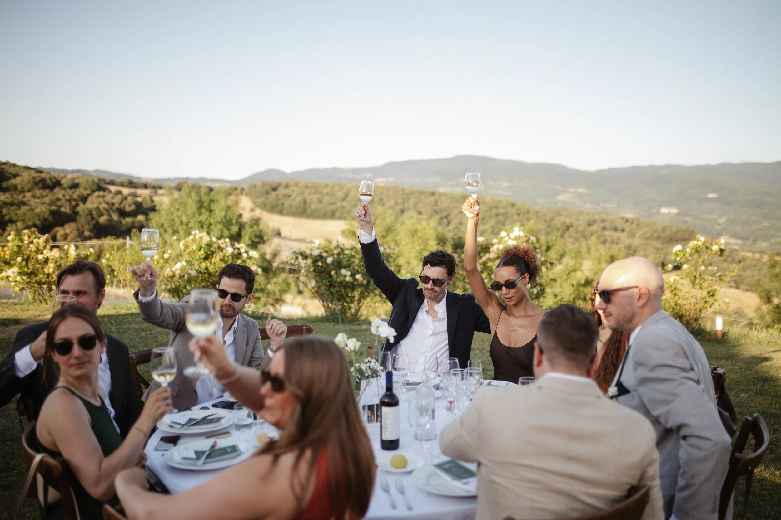 Relaxed and elegant Tuscany wedding dinner under the open sky, with natural white and green wedding styling, long summer evenings and an intimate atmosphere.