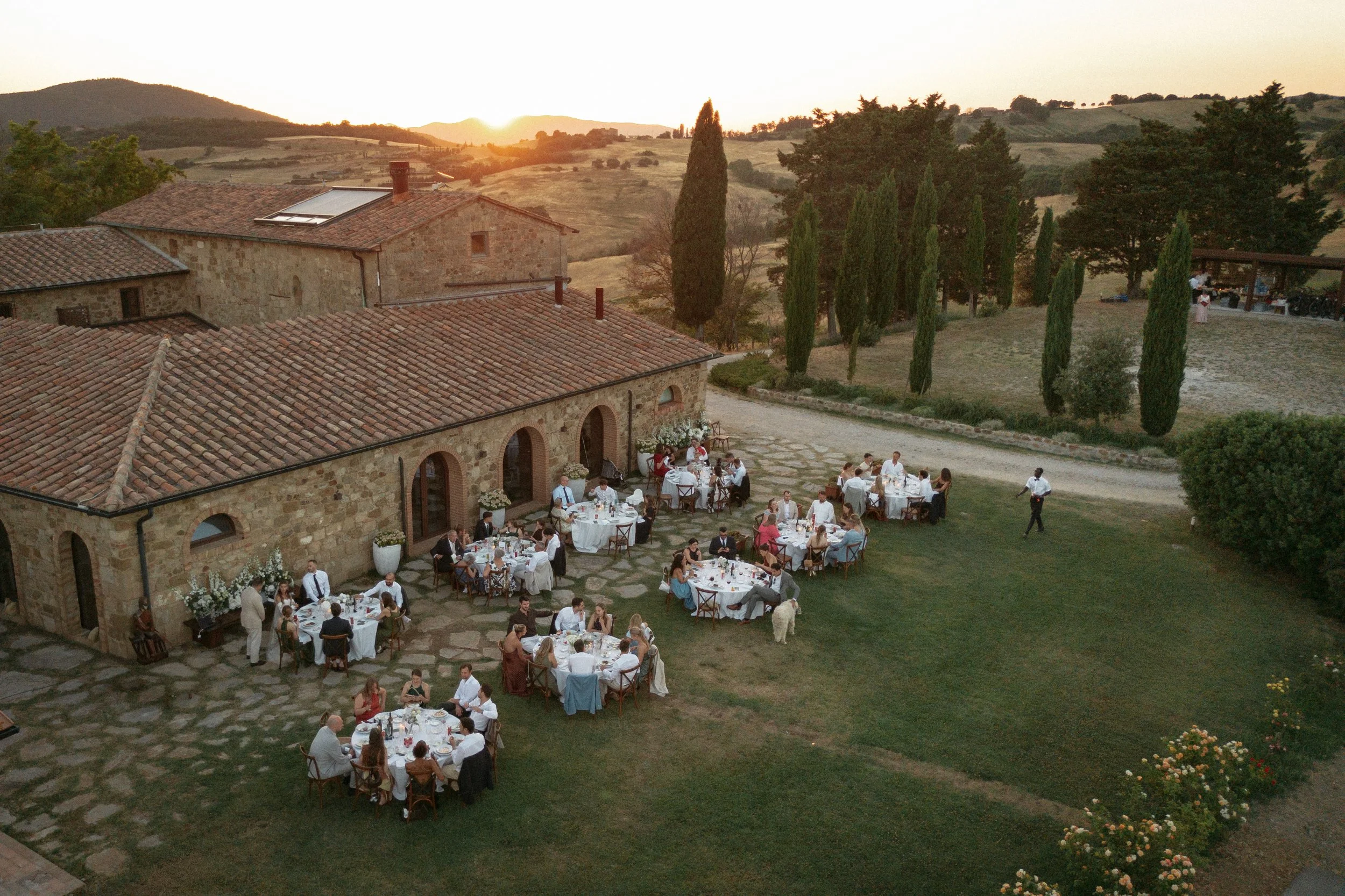 Relaxed and elegant Tuscany wedding dinner under the open sky, with natural white and green wedding styling, long summer evenings and an intimate atmosphere.