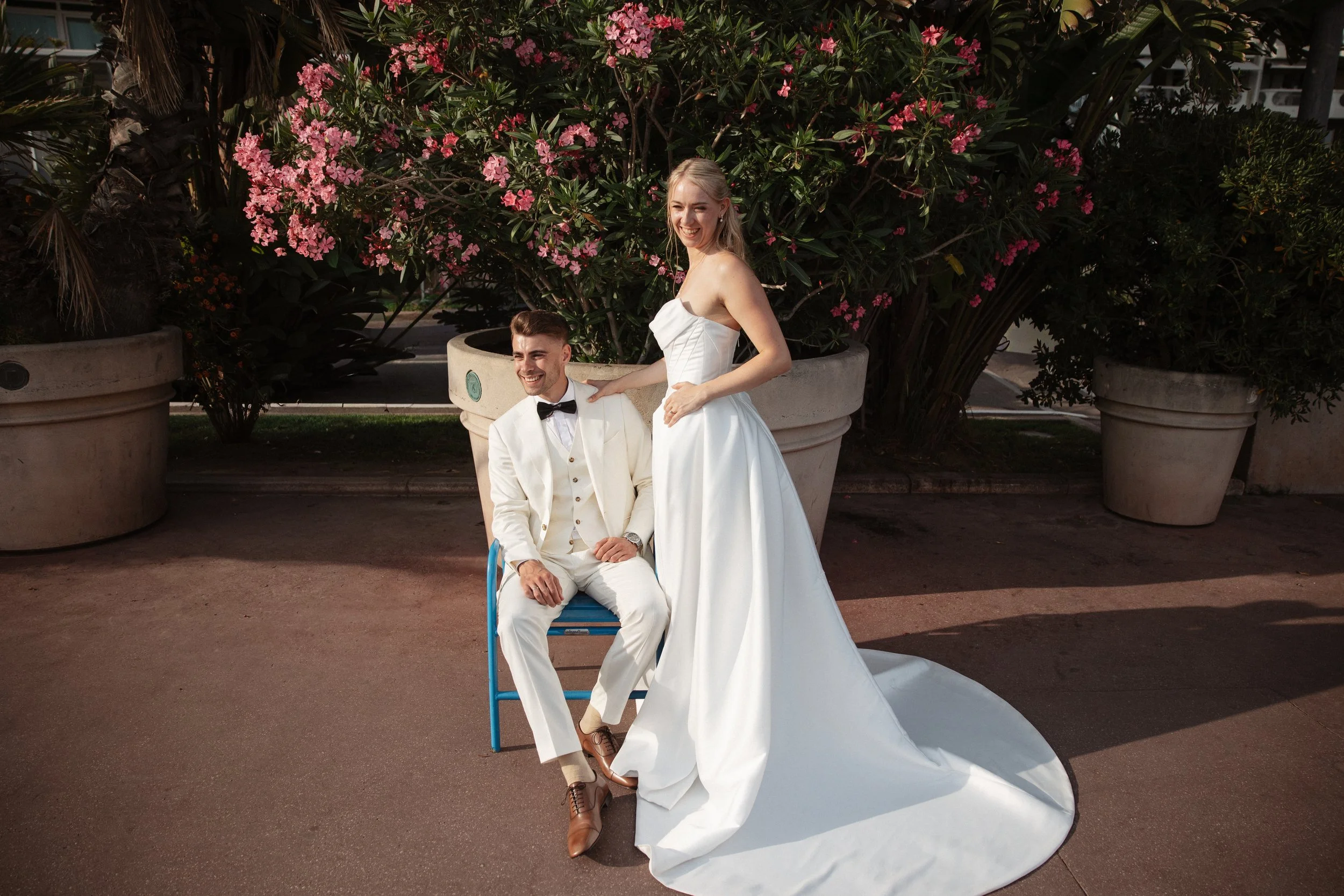 Elegant wedding portraits of the bride and groom along Boulevard de la Croisette in Cannes, featuring a white tuxedo, timeless bridal fashion, Mediterranean architecture, and the iconic French Riviera atmosphere.