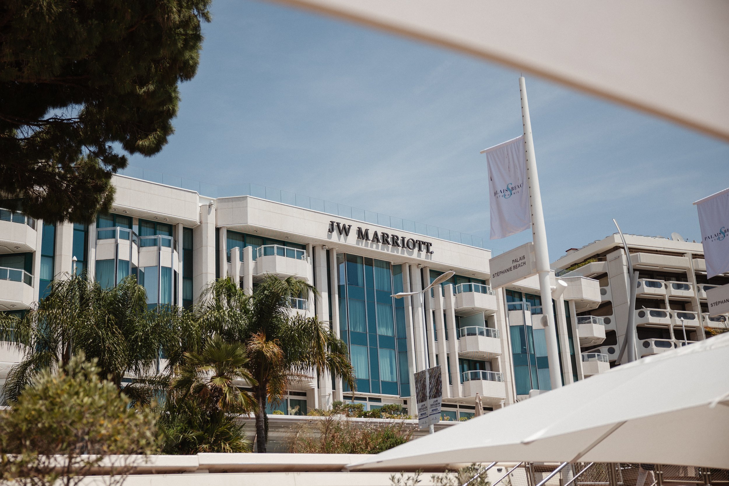 Outdoor wedding ceremony at Stephanie Beach in Cannes overlooking the Mediterranean Sea, surrounded by palm trees and the beautiful coastline of the French Riviera during an intimate luxury wedding.