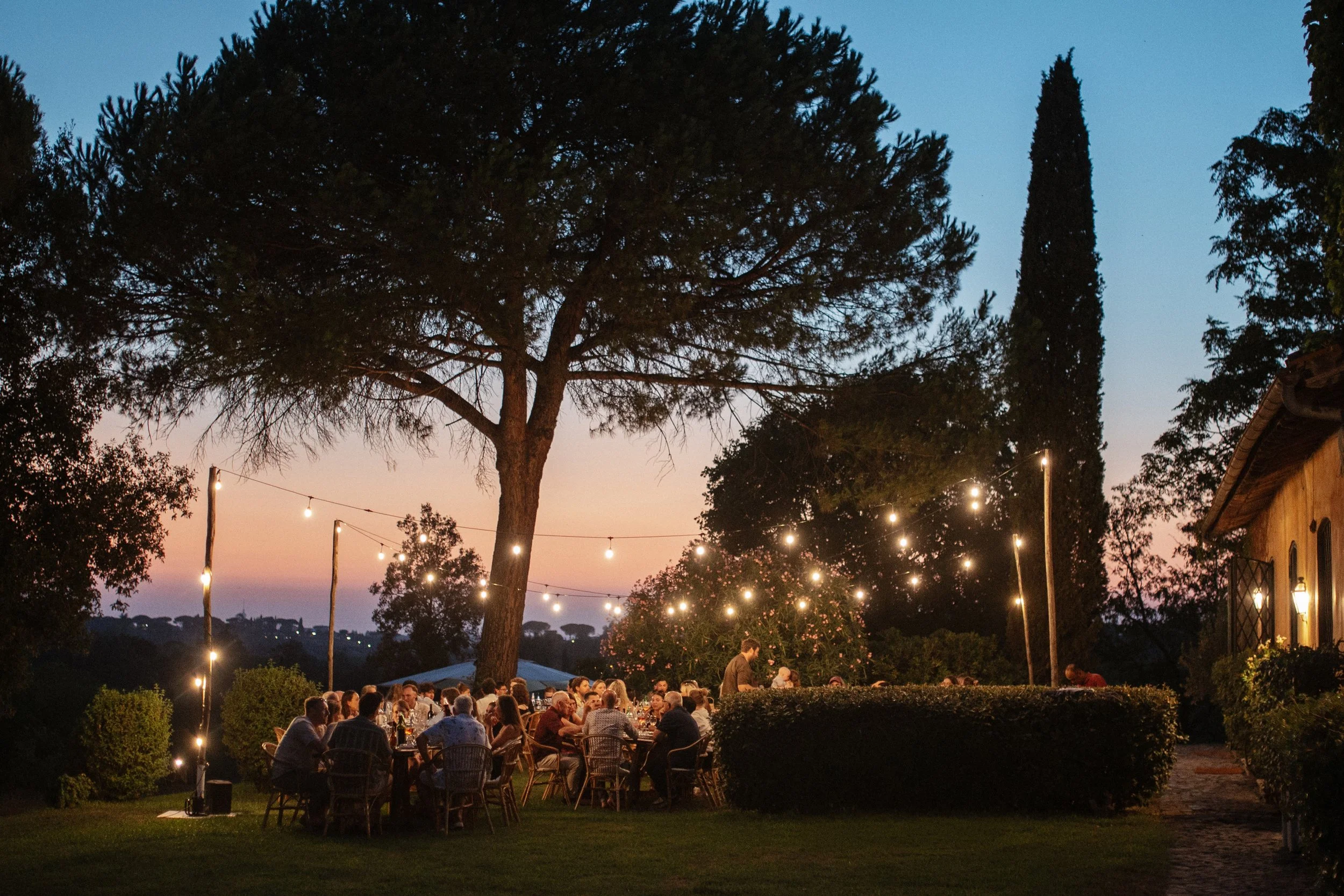 Relaxed welcome dinner at Casale del Gallo in Rome, with Selina and Jamie celebrating with their guests over pizza on a warm Italian summer evening.