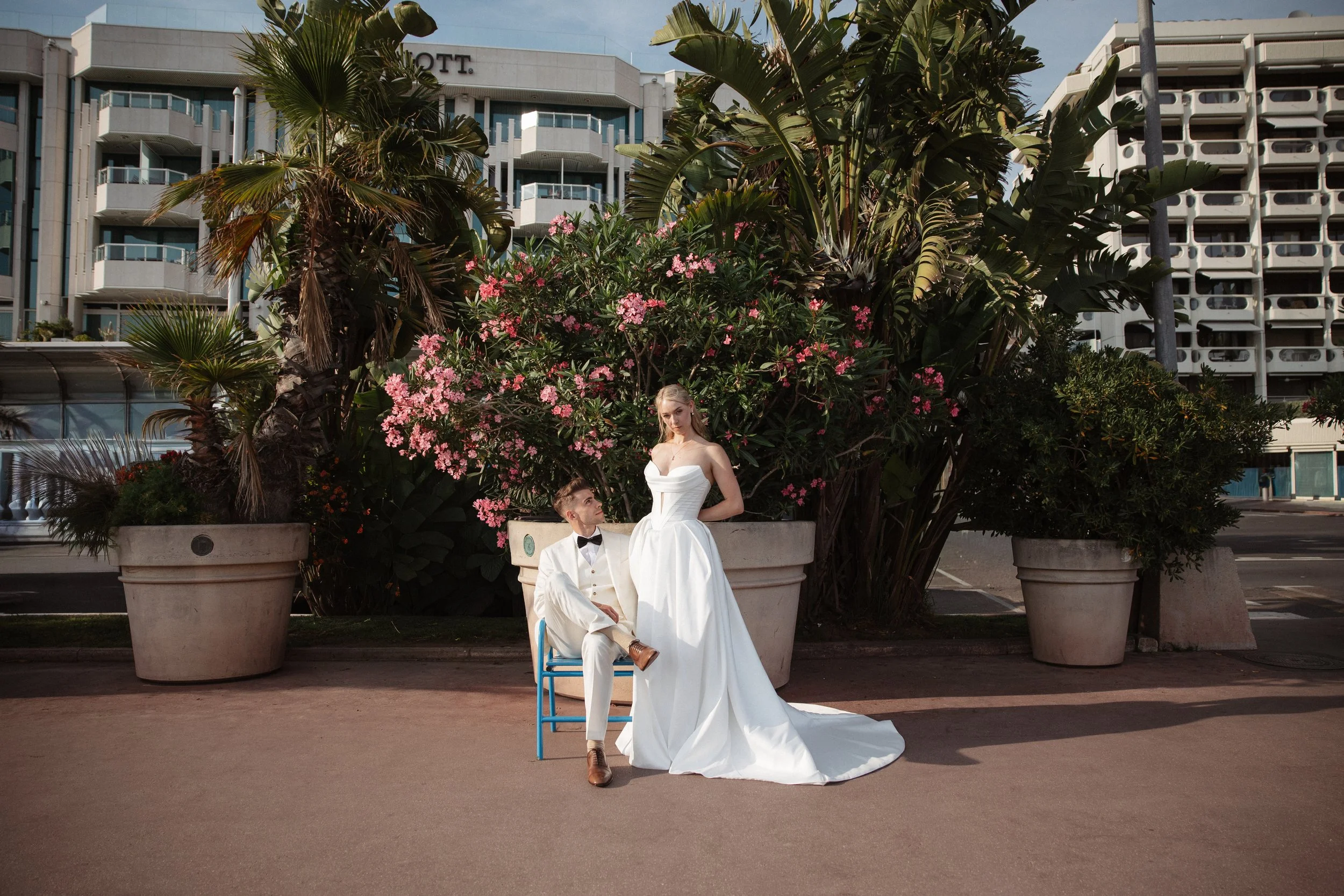 Elegant wedding portraits of the bride and groom along Boulevard de la Croisette in Cannes, featuring a white tuxedo, timeless bridal fashion, Mediterranean architecture, and the iconic French Riviera atmosphere.