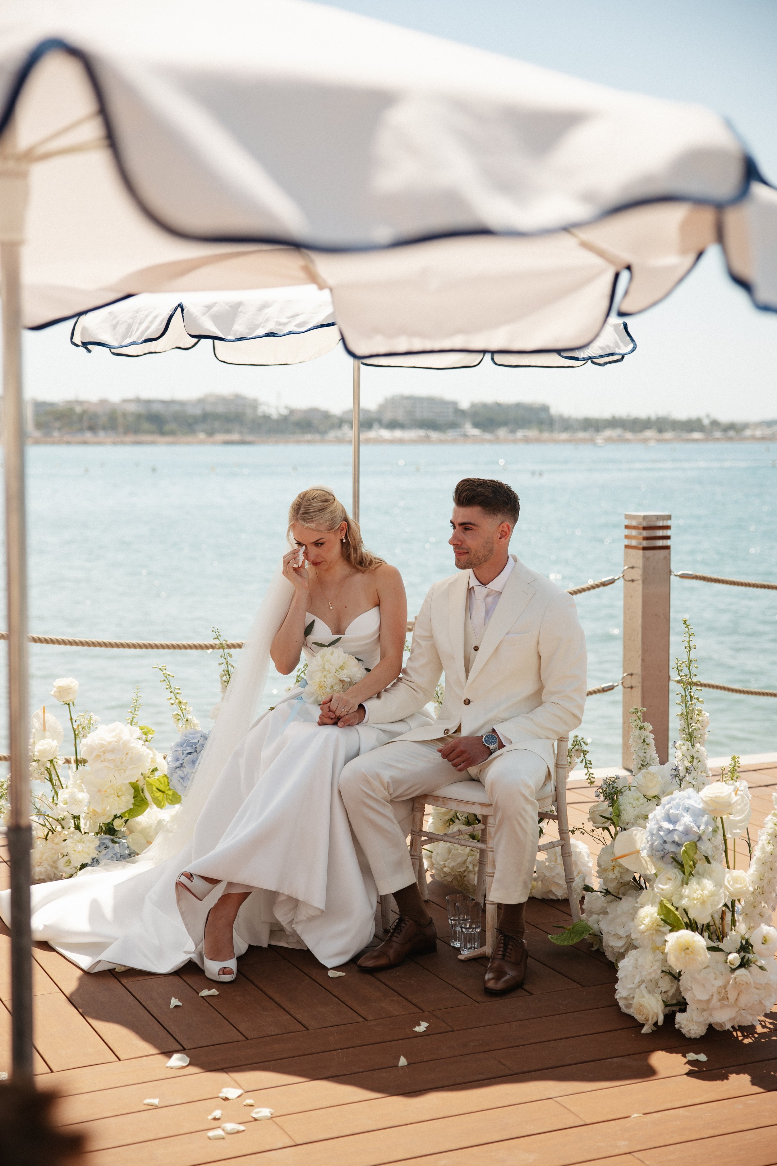 Outdoor wedding ceremony at Stephanie Beach in Cannes overlooking the Mediterranean Sea, surrounded by palm trees and the beautiful coastline of the French Riviera during an intimate luxury wedding.