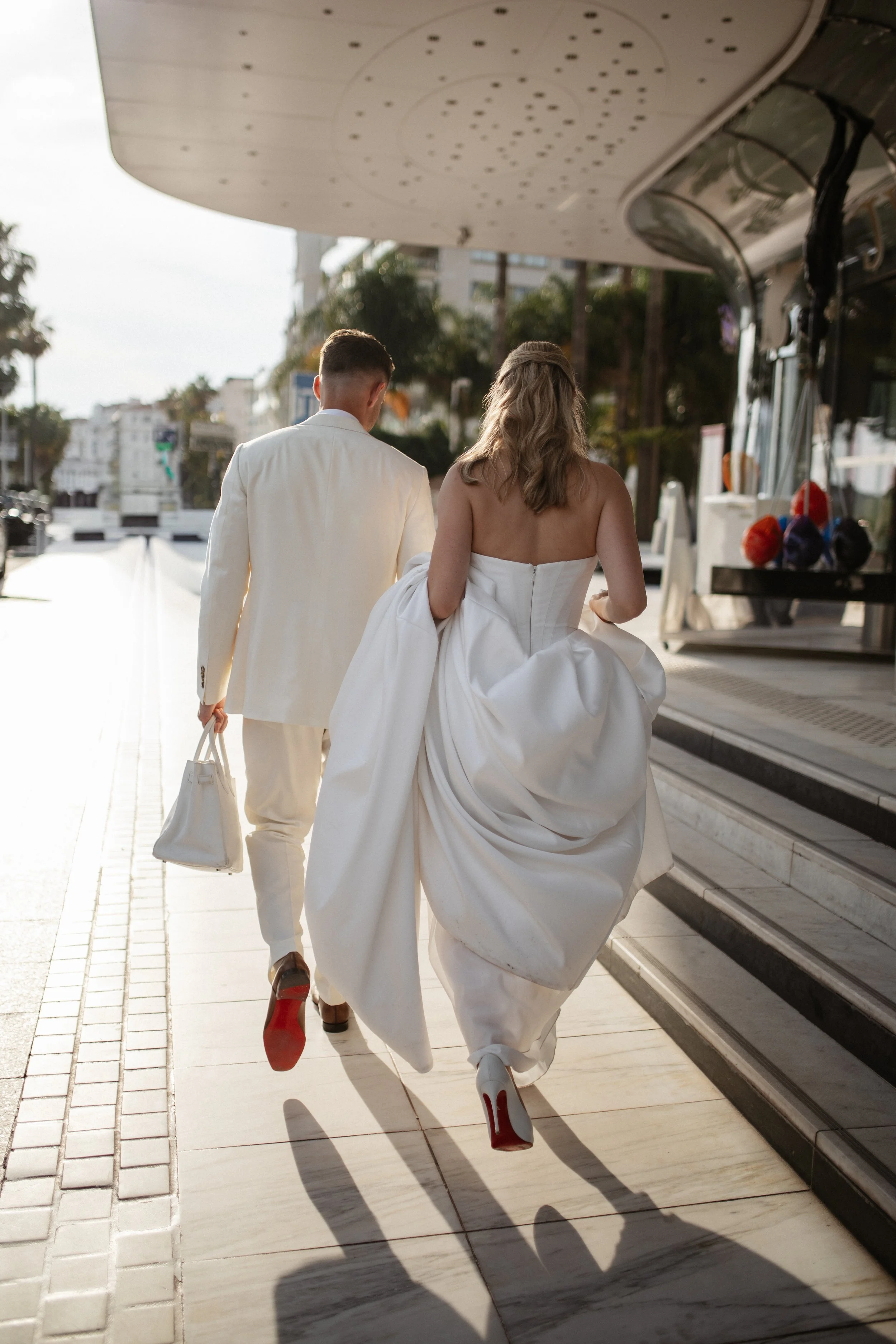 Elegant wedding portraits of the bride and groom along Boulevard de la Croisette in Cannes, featuring a white tuxedo, timeless bridal fashion, Mediterranean architecture, and the iconic French Riviera atmosphere.