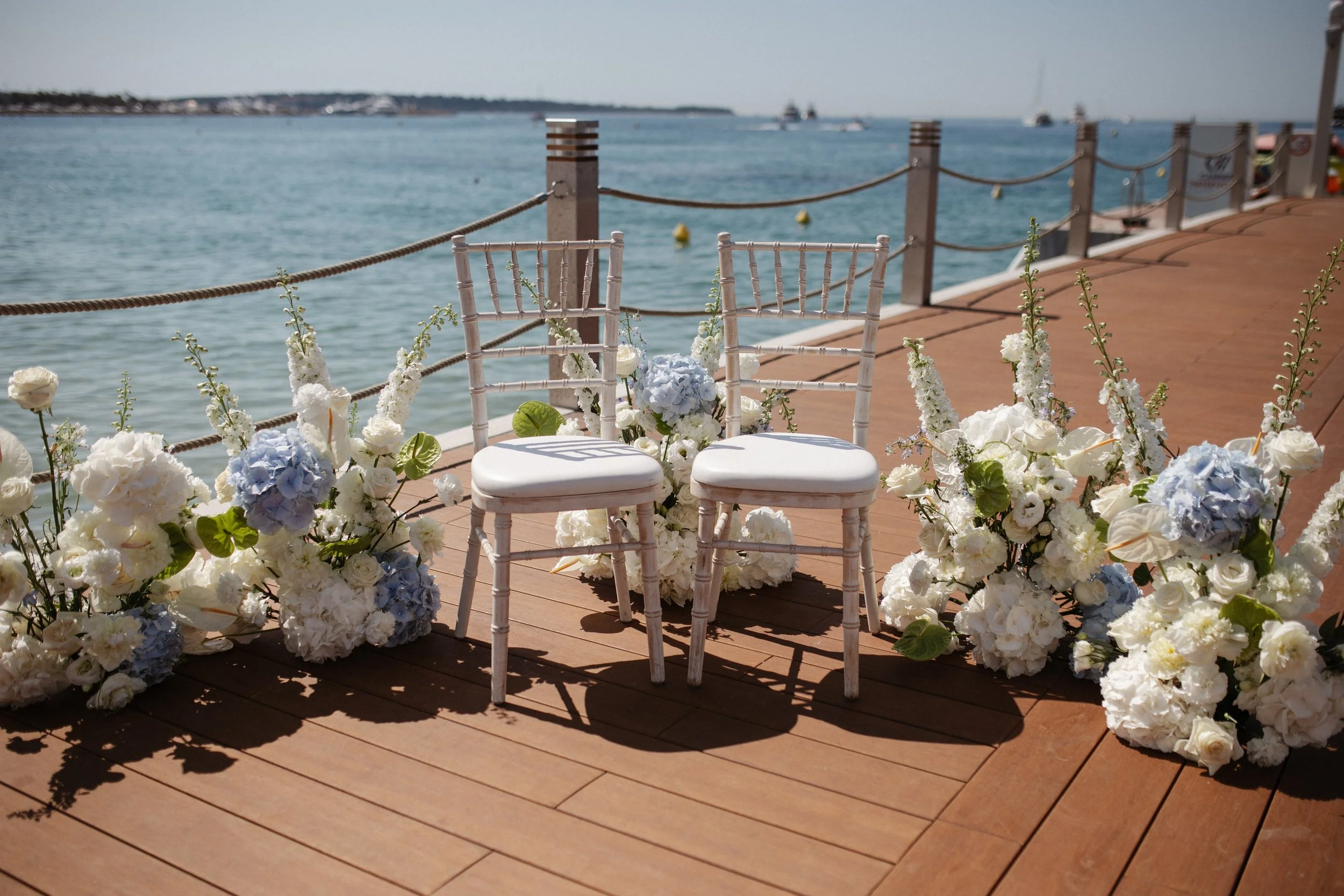 Outdoor wedding ceremony at Stephanie Beach in Cannes overlooking the Mediterranean Sea, surrounded by palm trees and the beautiful coastline of the French Riviera during an intimate luxury wedding.
