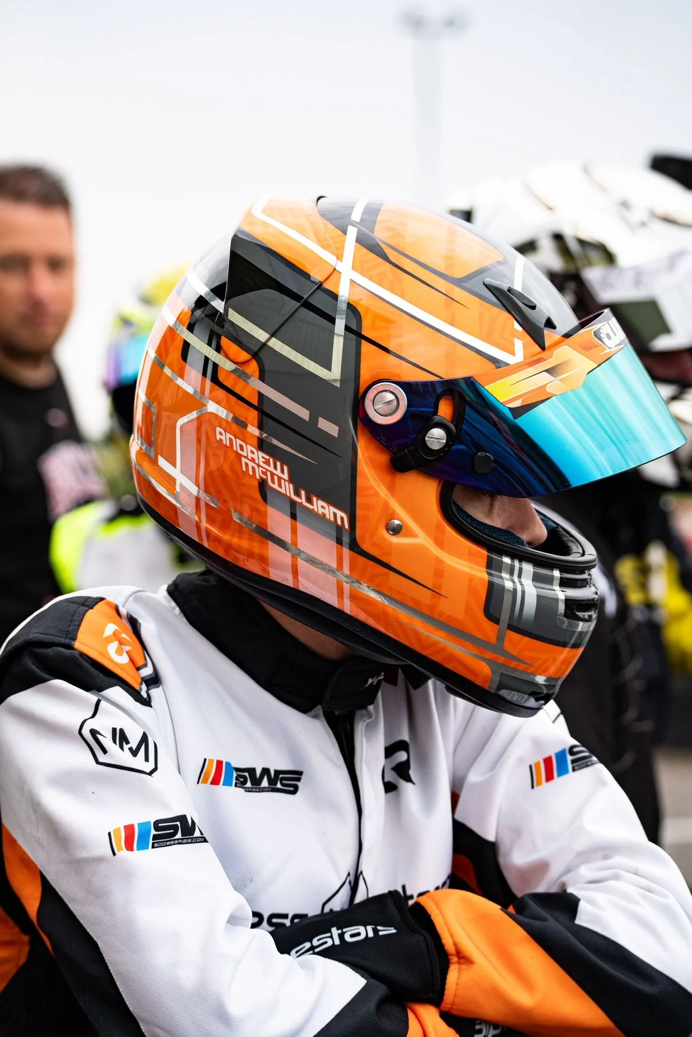 Go-kart racer wearing an orange helmet with name written on the side, participating in the British Universities Karting Championship."
