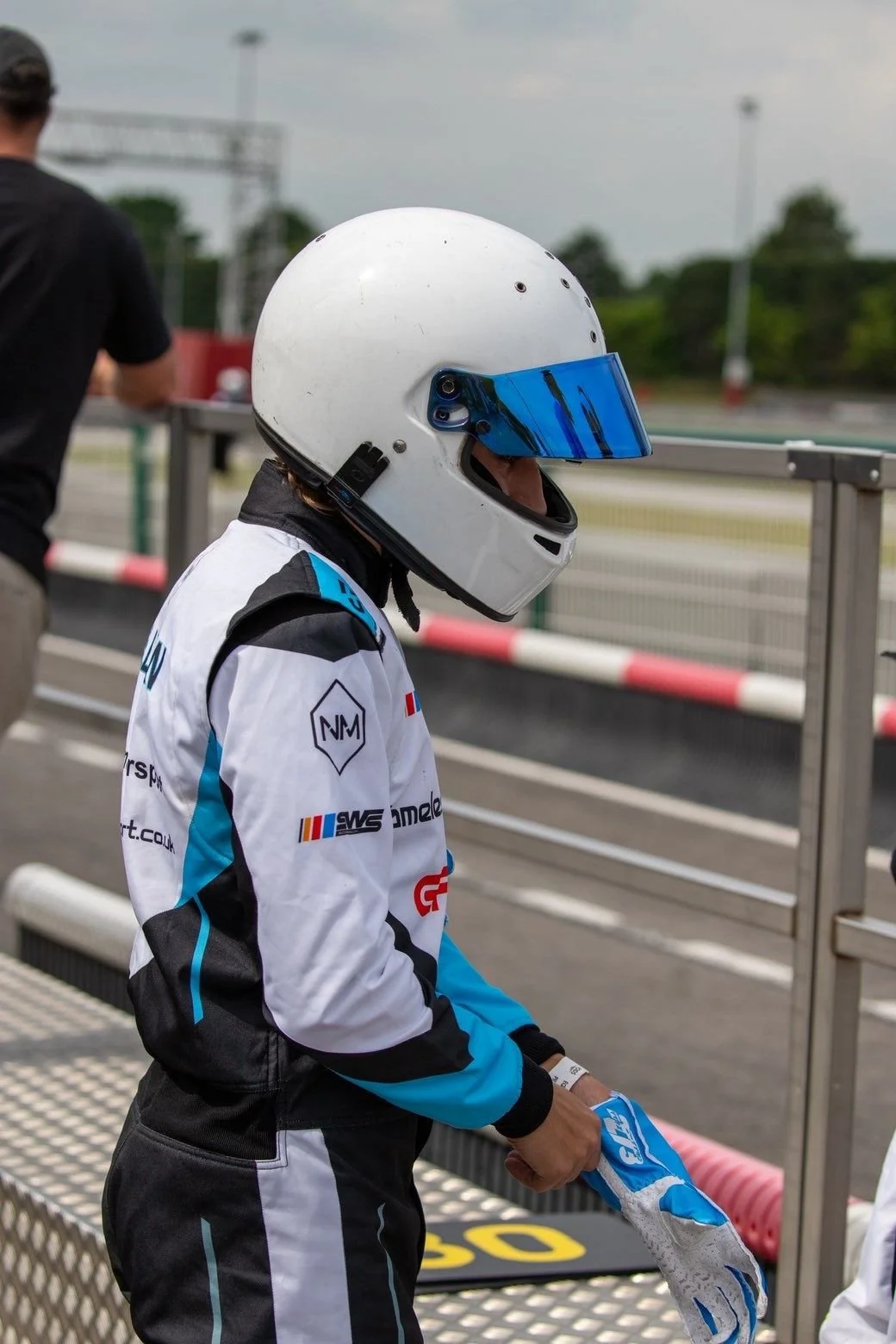 Person in a racing suit and helmet preparing for go-kart race.