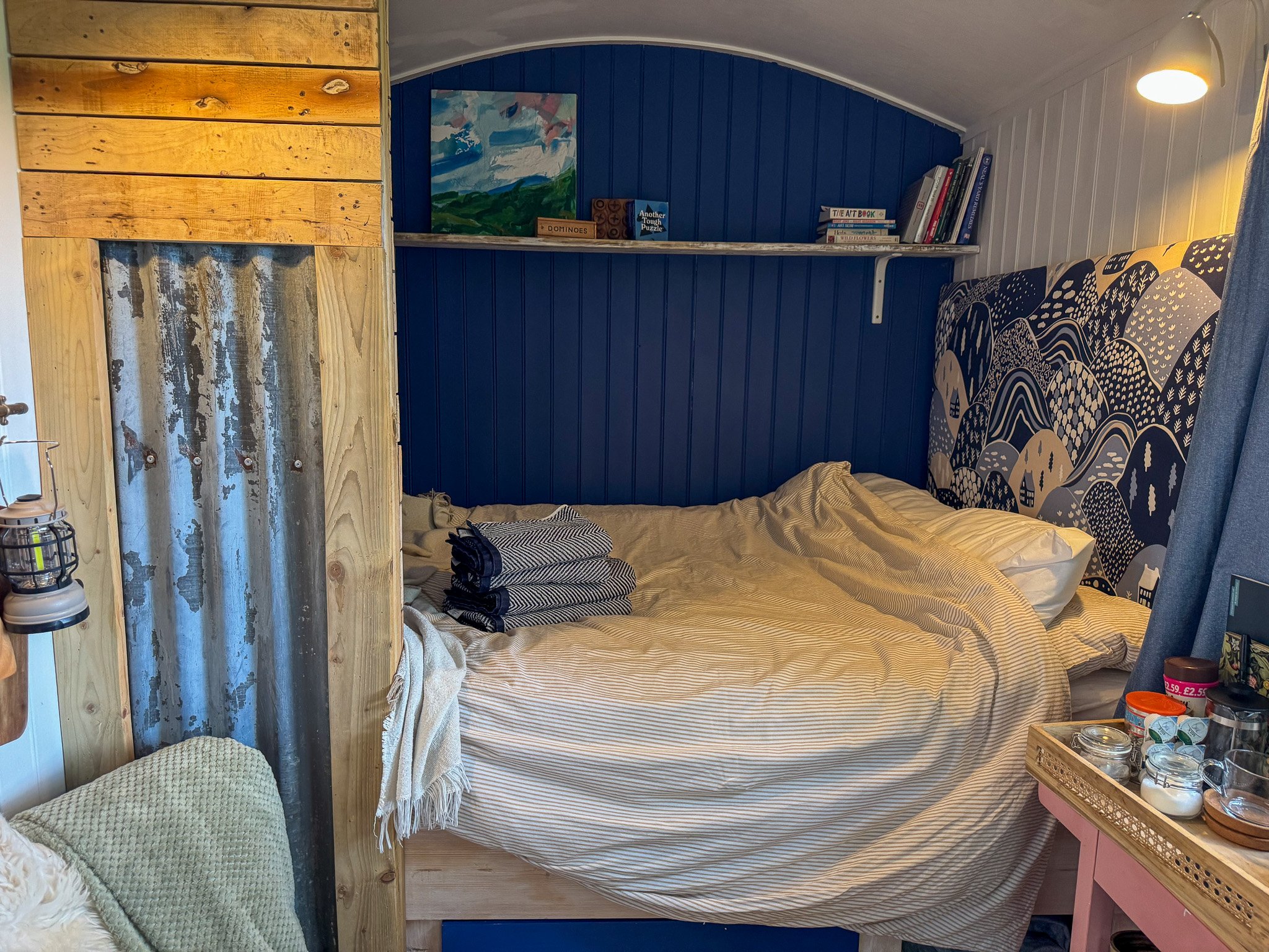Double bed inside the private off-grid shepherd's hut at Slow Glamping in Devon, featuring cosy furnishings and woodland-inspired décor.
