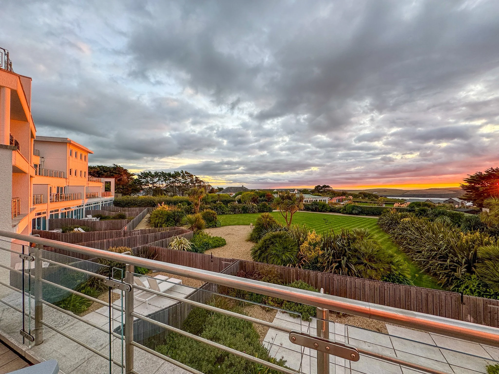 Balcony view overlooking the landscaped gardens and coastal sunset at St Moritz Hotel in Cornwall.