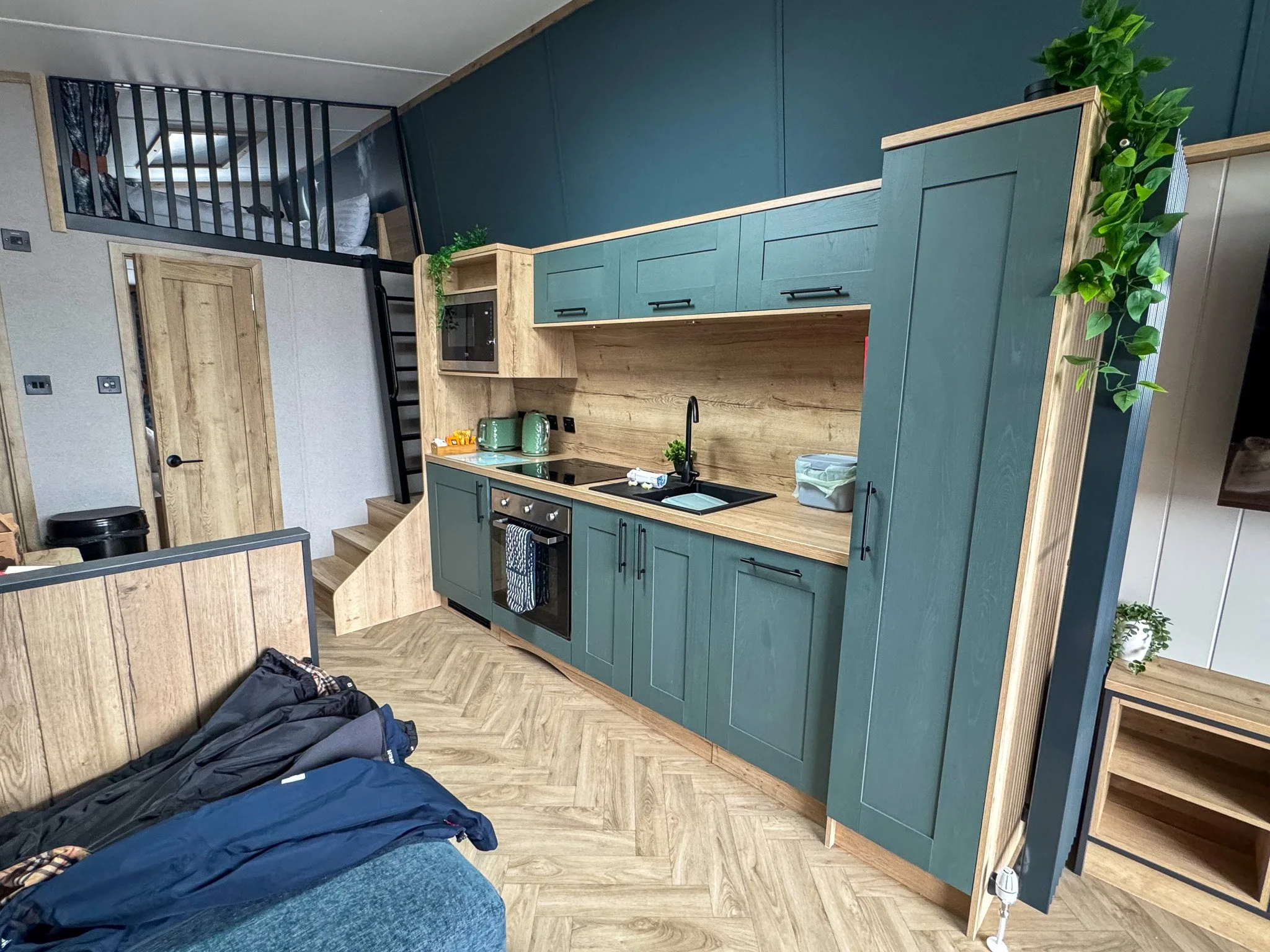 Open-plan kitchen and living area inside The Luxury Cornwall Hideaway at Trelay Holiday Park, featuring the fully equipped kitchen and children's mezzanine sleeping area.