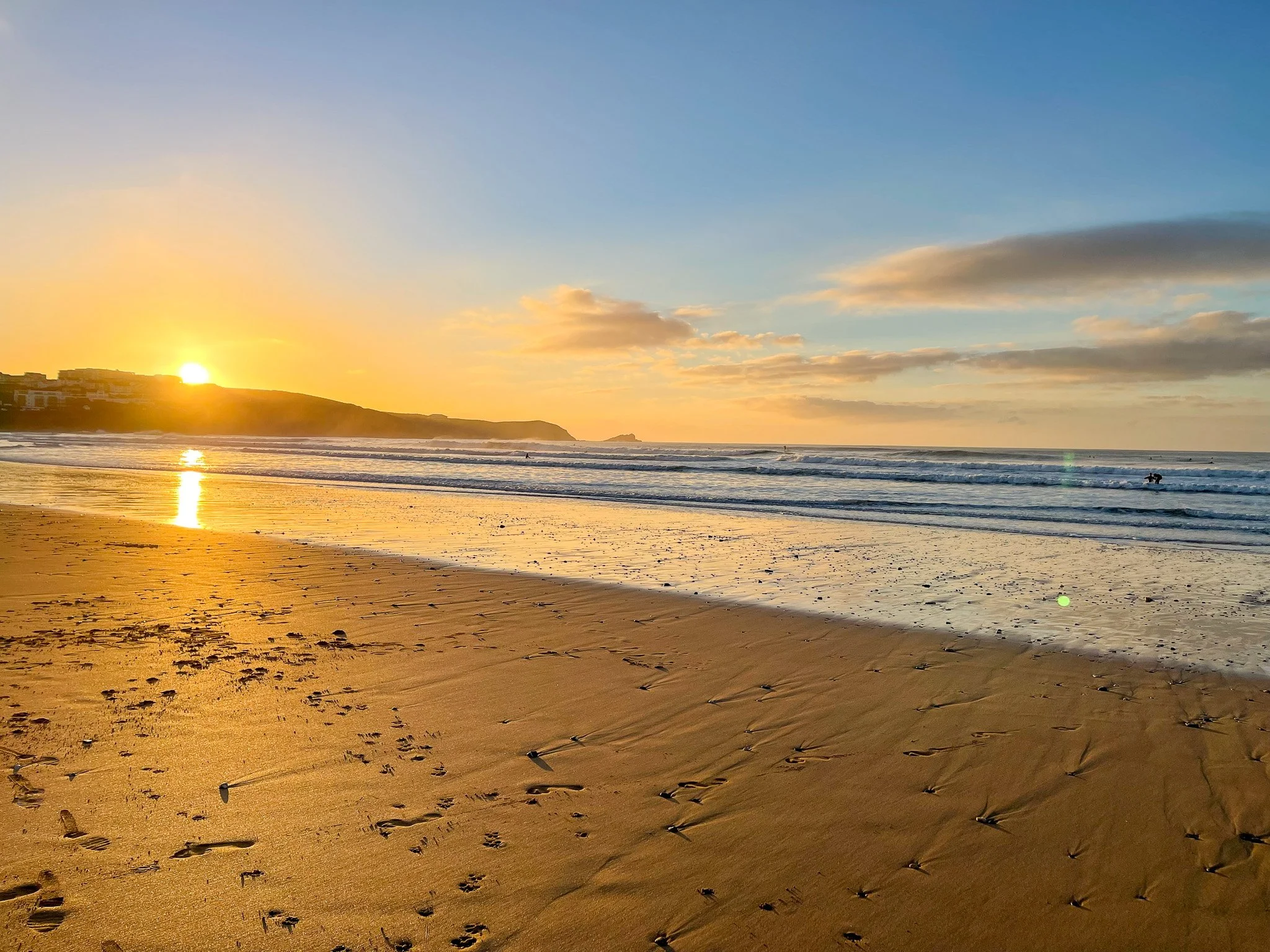 Sunset over Fistral Beach in Newquay, Cornwall with golden reflections on the sand
