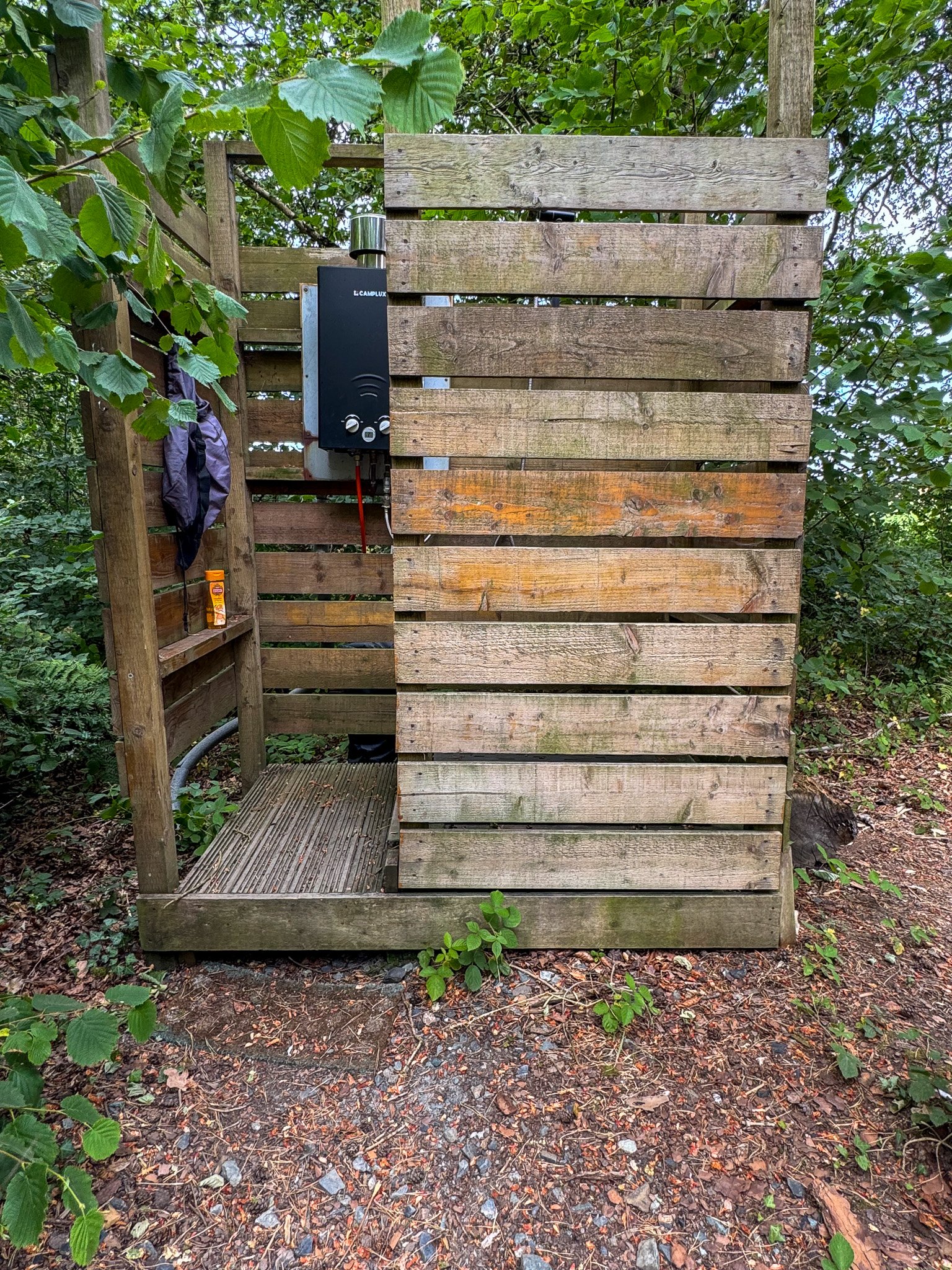 Private outdoor gas-powered shower at Slow Glamping in Devon, surrounded by peaceful woodland.