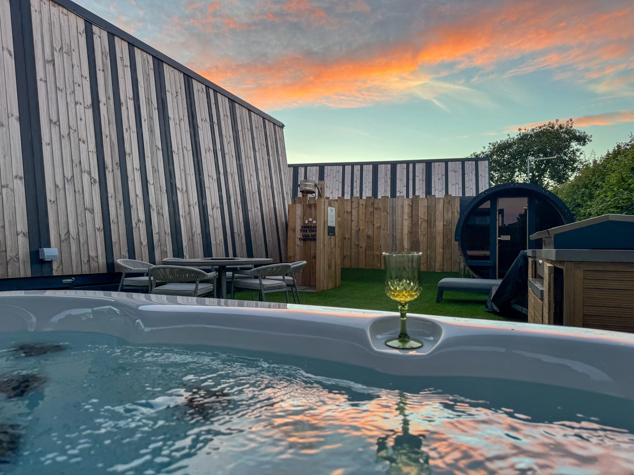 Private hot tub and outdoor sauna at The Luxury Cornwall Hideaway at Trelay Holiday Park during sunset.