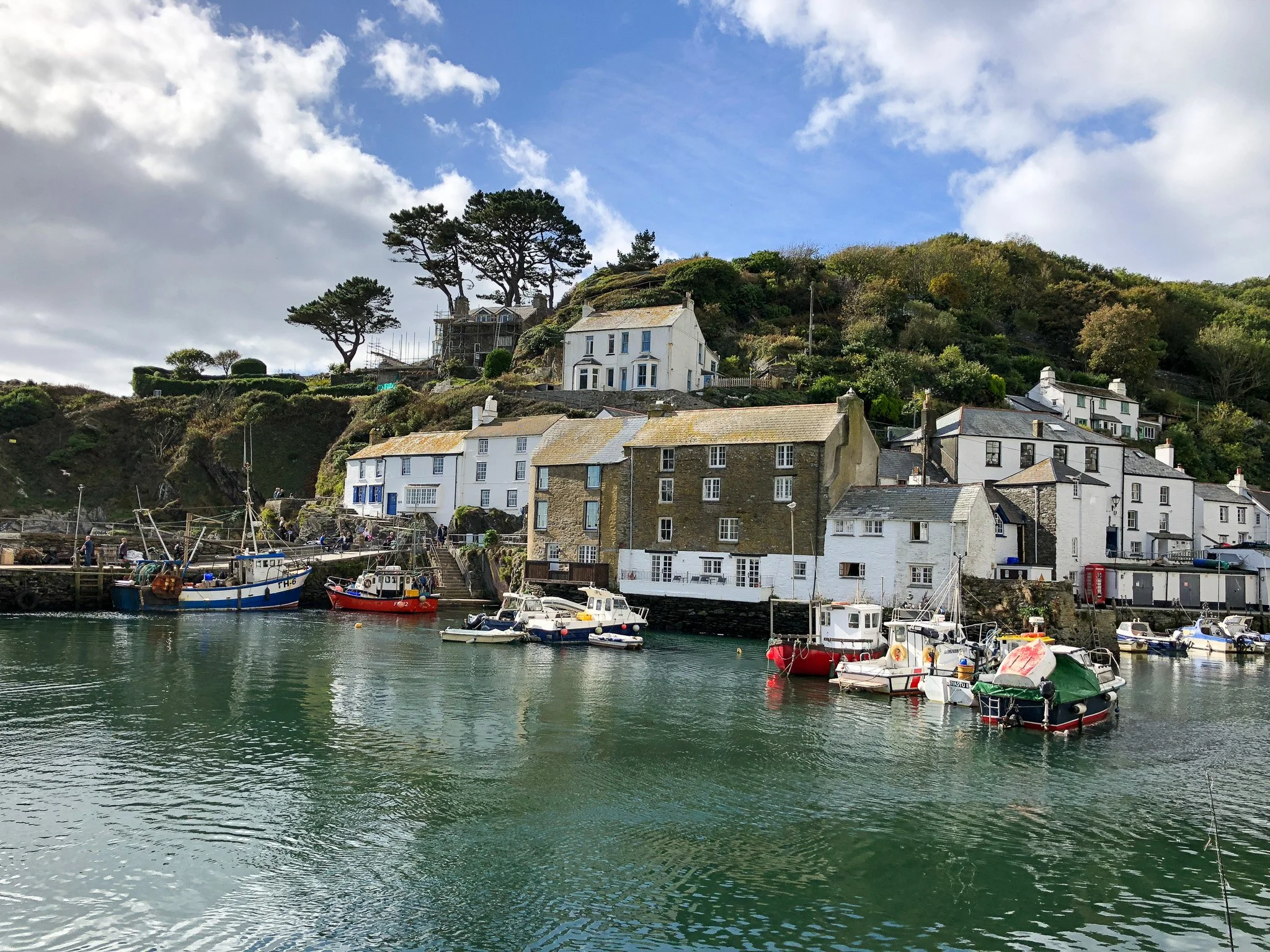 View across Polperro Harbour in Cornwall, showing traditional fishing boats, historic cottages and the picturesque hillside overlooking the village.