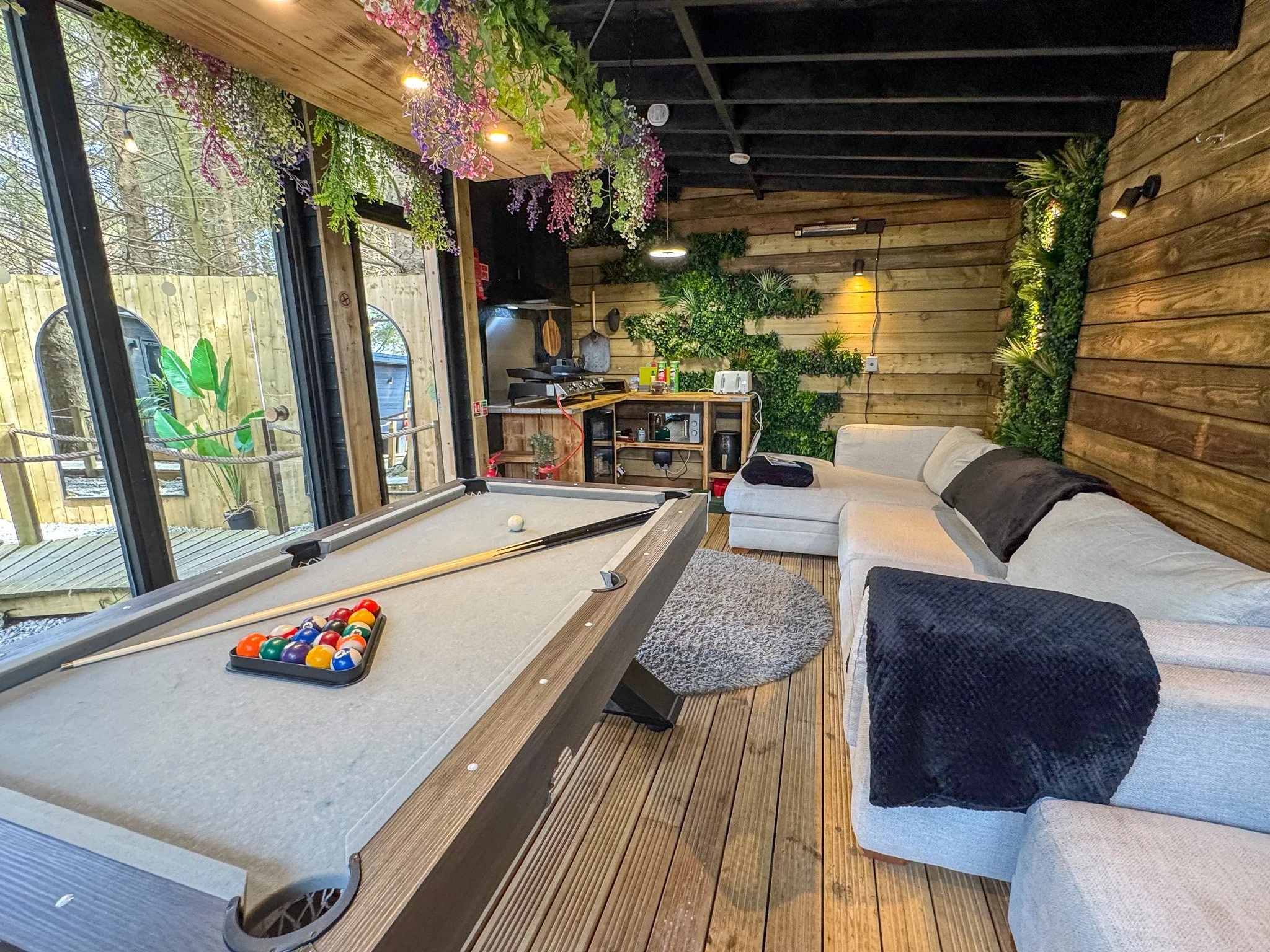 Secret Garden Glamping Cornwall entertainment space with pool table, sofa and covered outdoor seating area