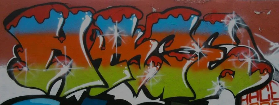 Graffiti coloré avec des effets de brillance sur un mur.