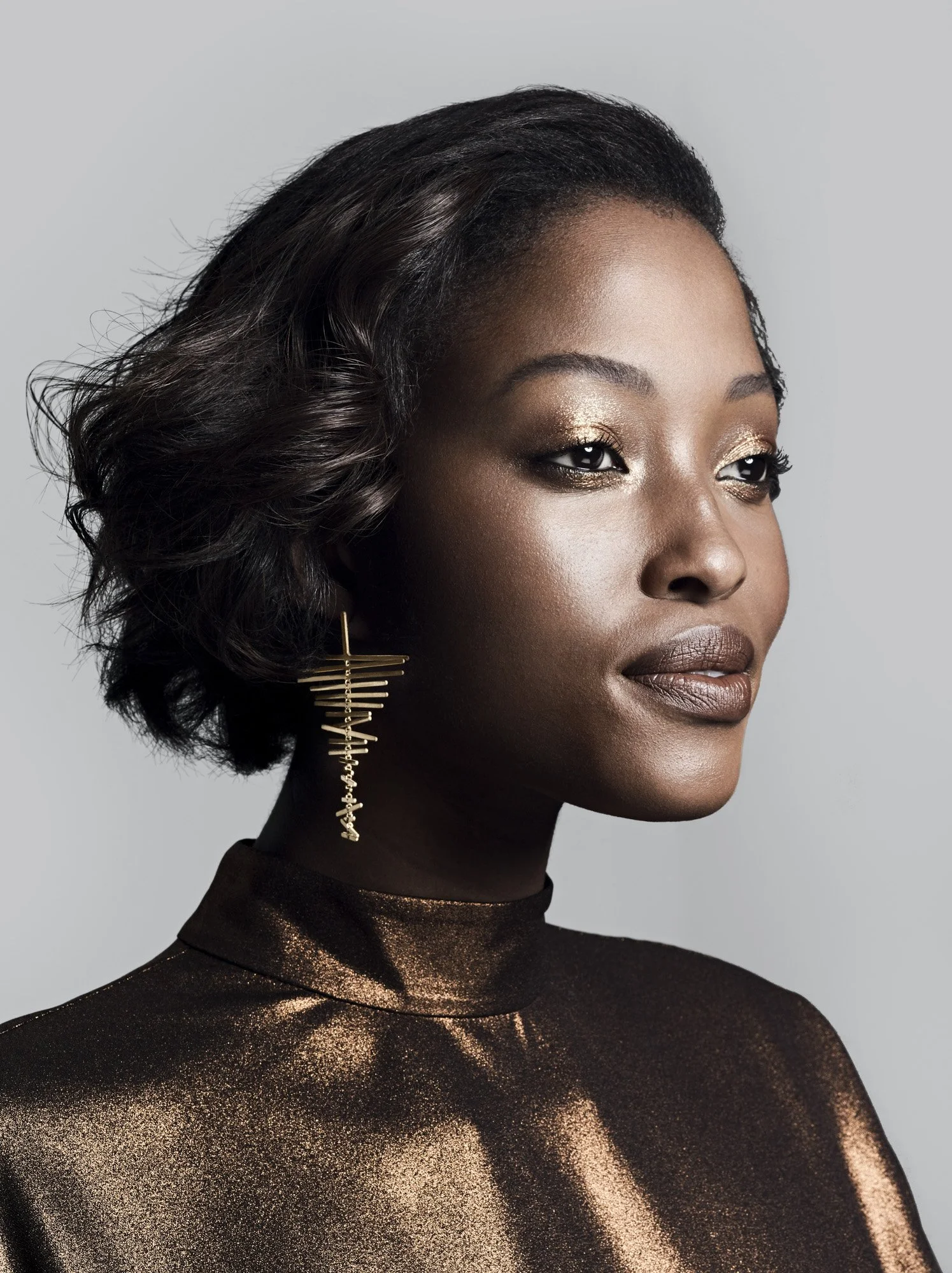 Sculptural gold earring on deep skin, jewellery photography London by Benjamin Kaufmann