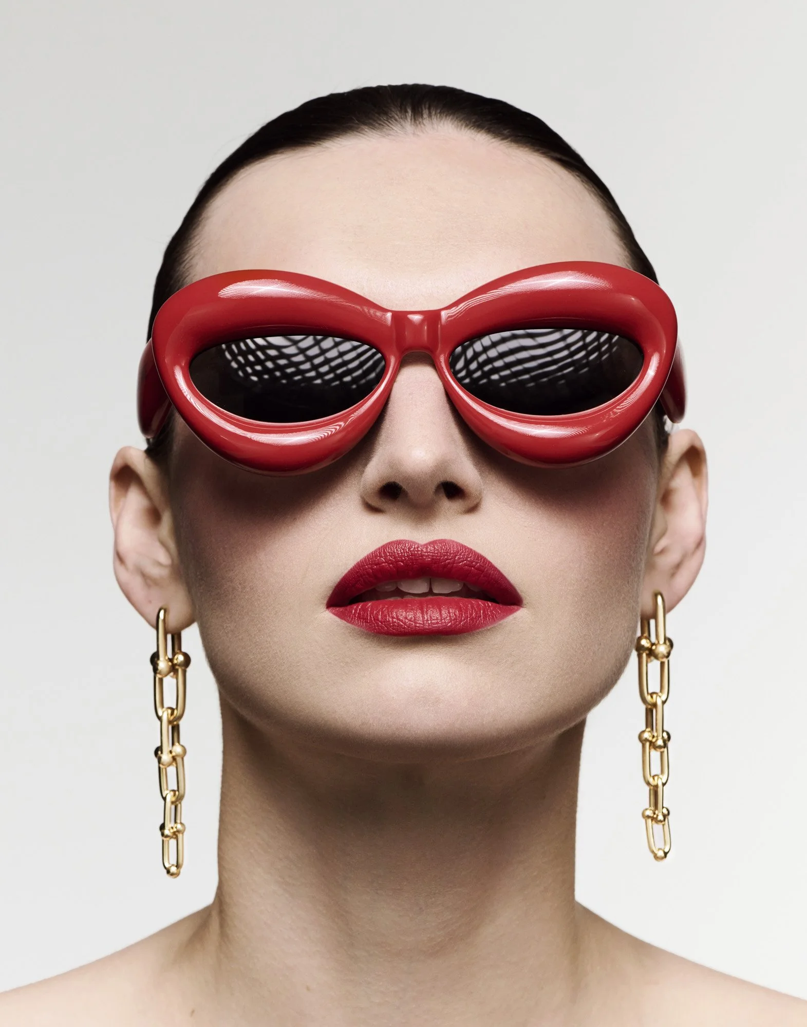Red sunglasses and chain earrings, eyewear photography London by Benjamin Kaufmann